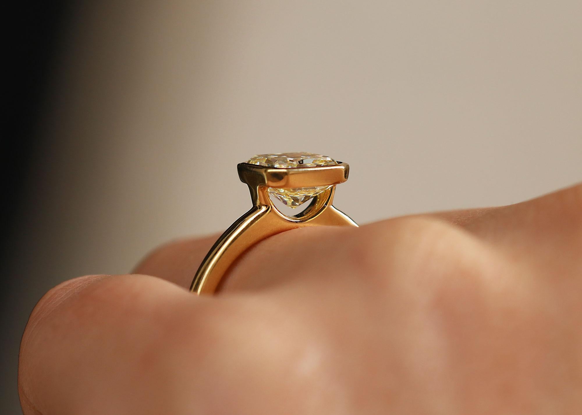 New  to our collection is this 2.09 carat natural fancy yellow diamond solitaire engagement ring. The simplicity of the rich, 18k yellow gold bezel setting adds warmth to the beautiful golden color of this earth-mined diamond. The expertly faceted