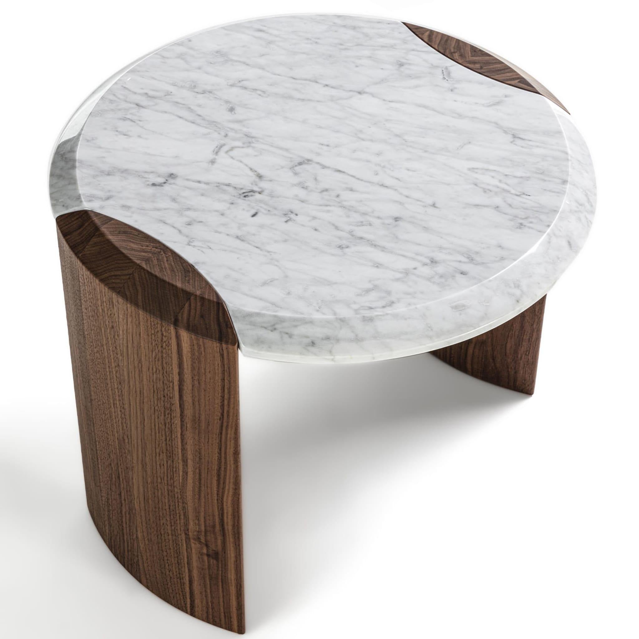 An elegant seamless joint distinguishes the exclusive series of tables this side table belongs to. The structural layout harmoniously coexists with a neat contrast of hues and finishes between the prized Carrara marble top and the almond-cut legs,