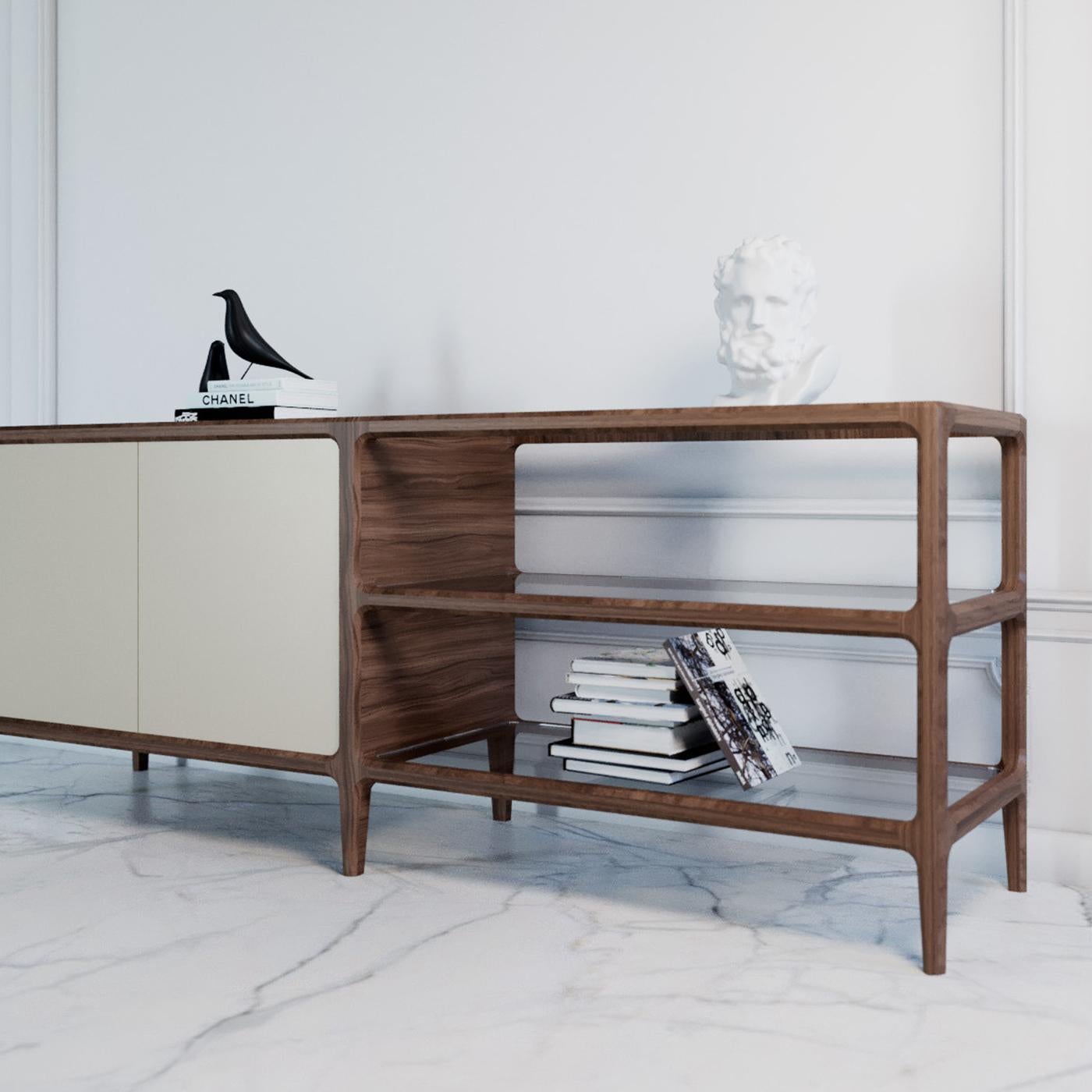 The skillful combination of prized details on an essential ash frame makes this sideboard a one-of-a-kind piece. Its solid structure stands on six feet and comprises an open shelving unit with two glass shelves and a regular unit featuring two doors
