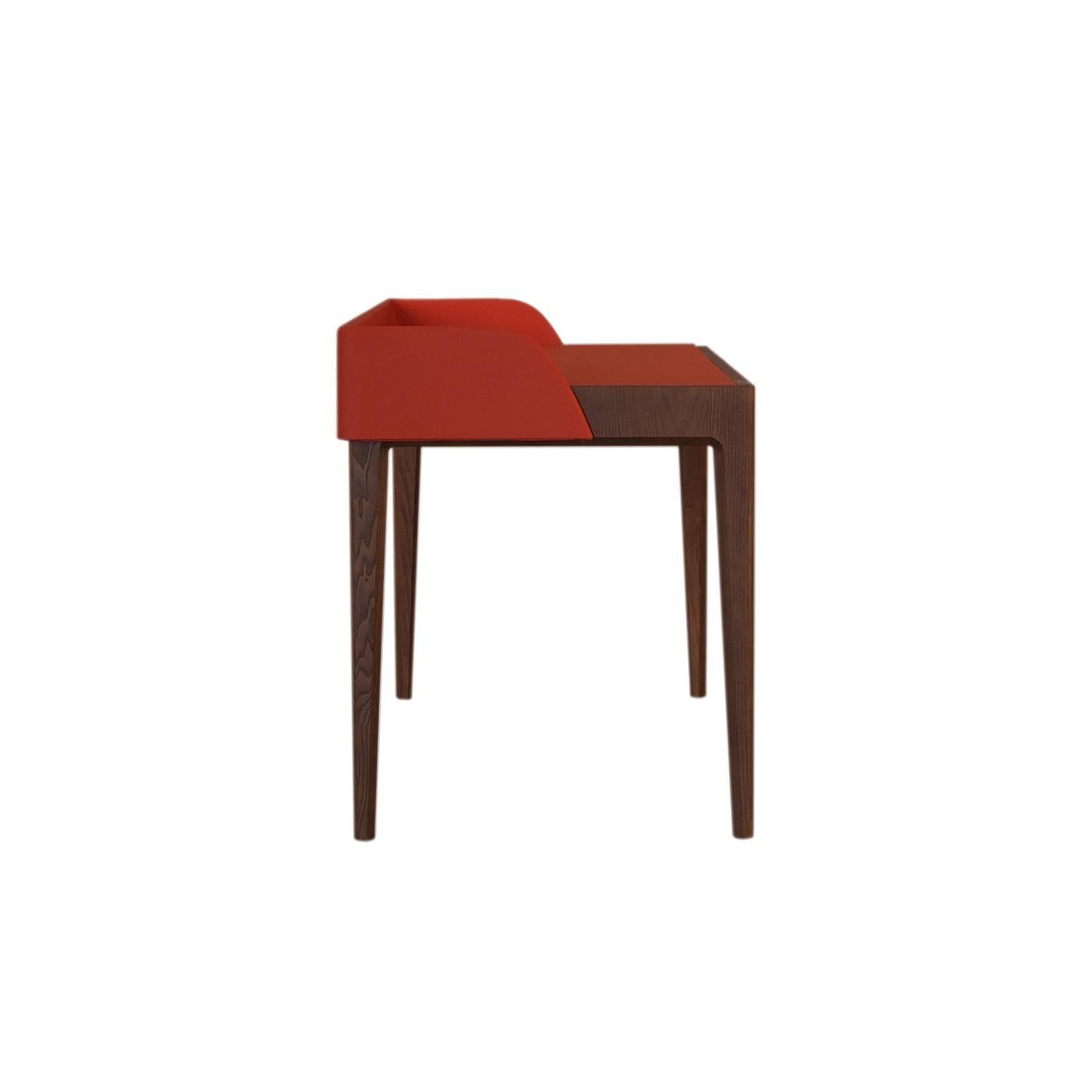 The glamorous combination of the leather's red hues and the ash wood's warm walnut finish renders this outstanding desk a captivating object of functional decor. The slender frame boasts comprises four tapered legs sustaining the top equipped with a