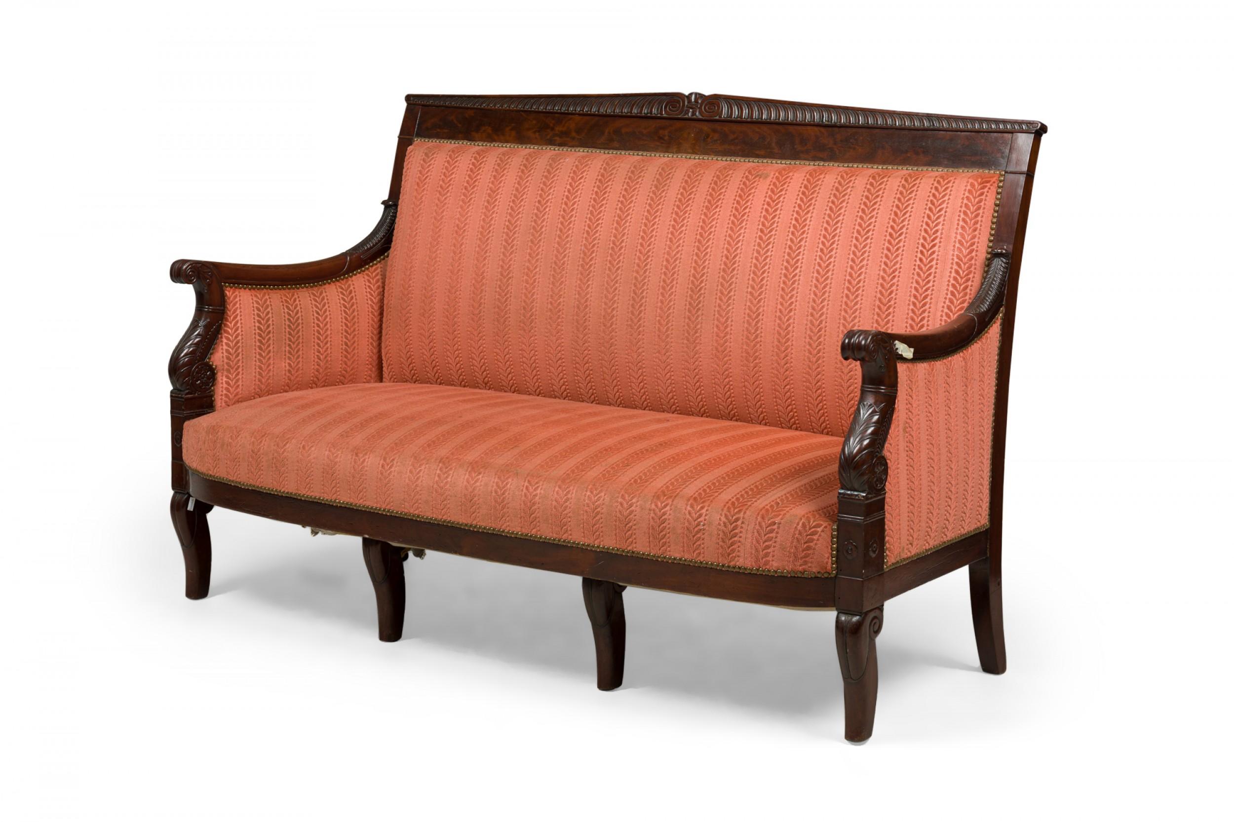 French Empire-style mahogany settee with a carved frame and striped blush pink and red upholstered seat, arms and back. (BELLANGER).