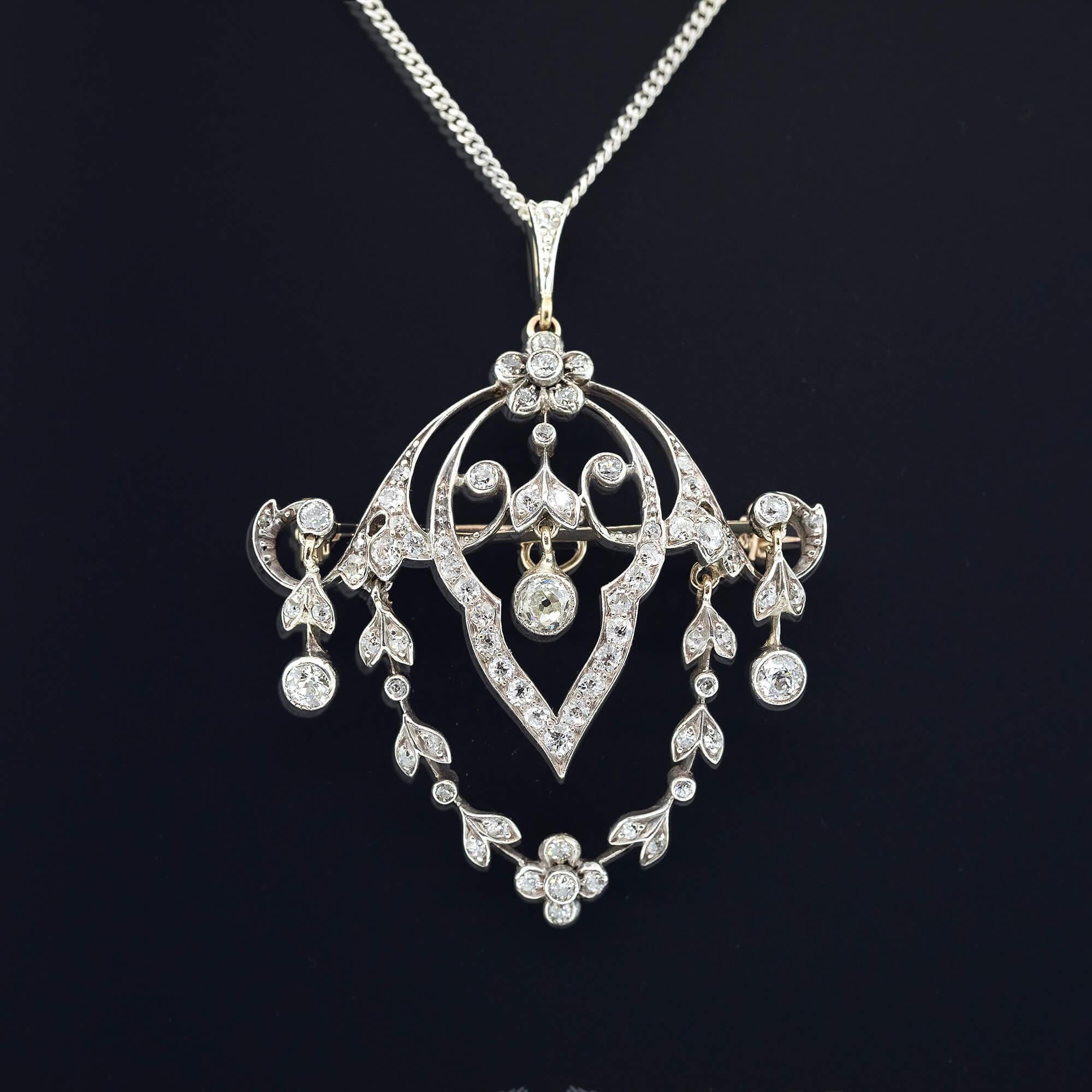 Belle Epoque diamond set convertible brooch/pendant with a collapsible pendant runner and removable brooch pin. Featuring florals, leaves, scrolls and drops. Chain sold separately.

Diamonds:
One 0.28ct old mine cut diamonds I-K, I1 material
Two