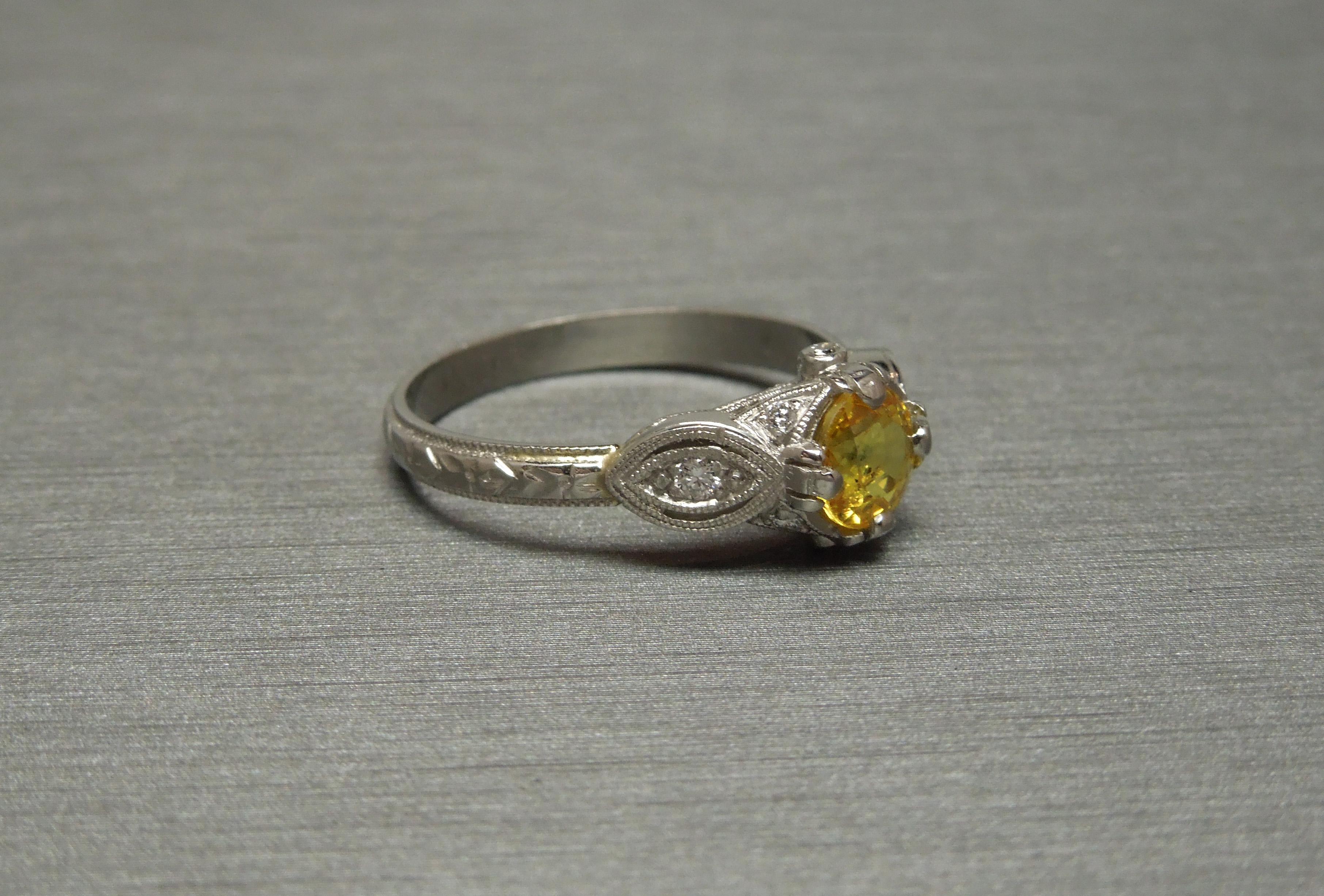 This Belle Époque Sapphire Ring features a central Round cut 1.10 carat Natural Canary Yellow Sapphire at 5.9mm in diameter, securely set in a 4-Prong setting. With a total of 8 Nearly Colorless Nearly Flawless Round Brilliant cut Accent Diamonds