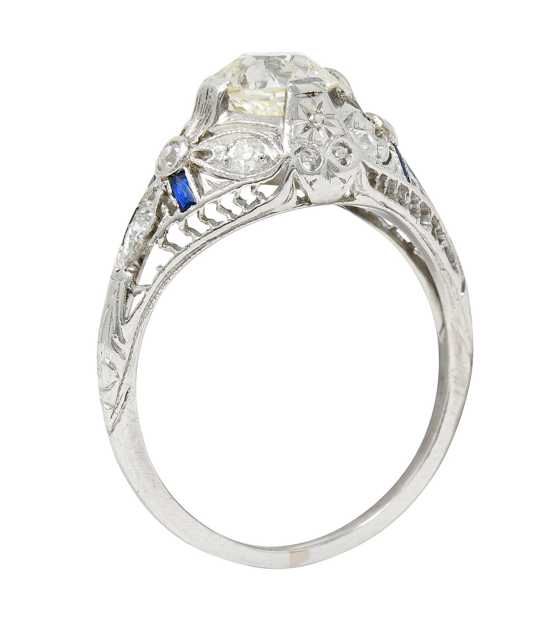 Featuring an old European cut diamond weighing 0.98 carat - M color with VS1 clarity

Set by wide stylized prongs in a bombè style mounting with stylized trefoil shoulders

Accented by calibrè cut synthetic sapphires - well matched in bright blue