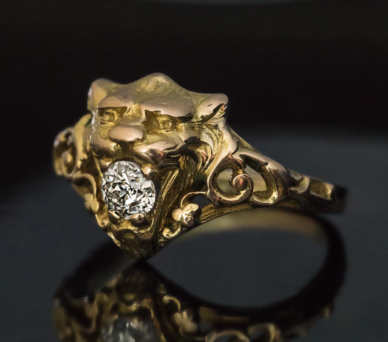 Circa 1890

This antique 14K gold unisex ring is finely modeled as the head of a lion with a sparkling bright white old mine cut diamond in its mouth. The lion is flanked by openwork shoulders with scrolling designs.

The diamond measures 4.68 x