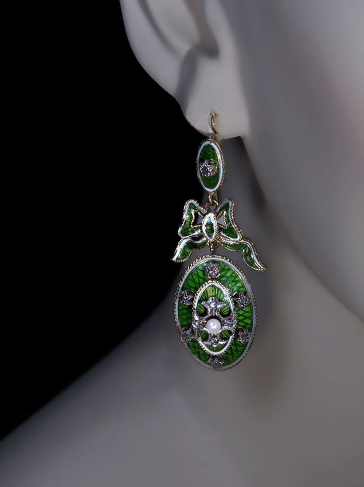 Circa 1890

This magnificent pair of Belle Époque antique 14K gold earrings of cross, star and bow motif features fine quality green guilloche and white opaque enamels. The earrings are further embellished with two pearls and 22 rose cut diamonds