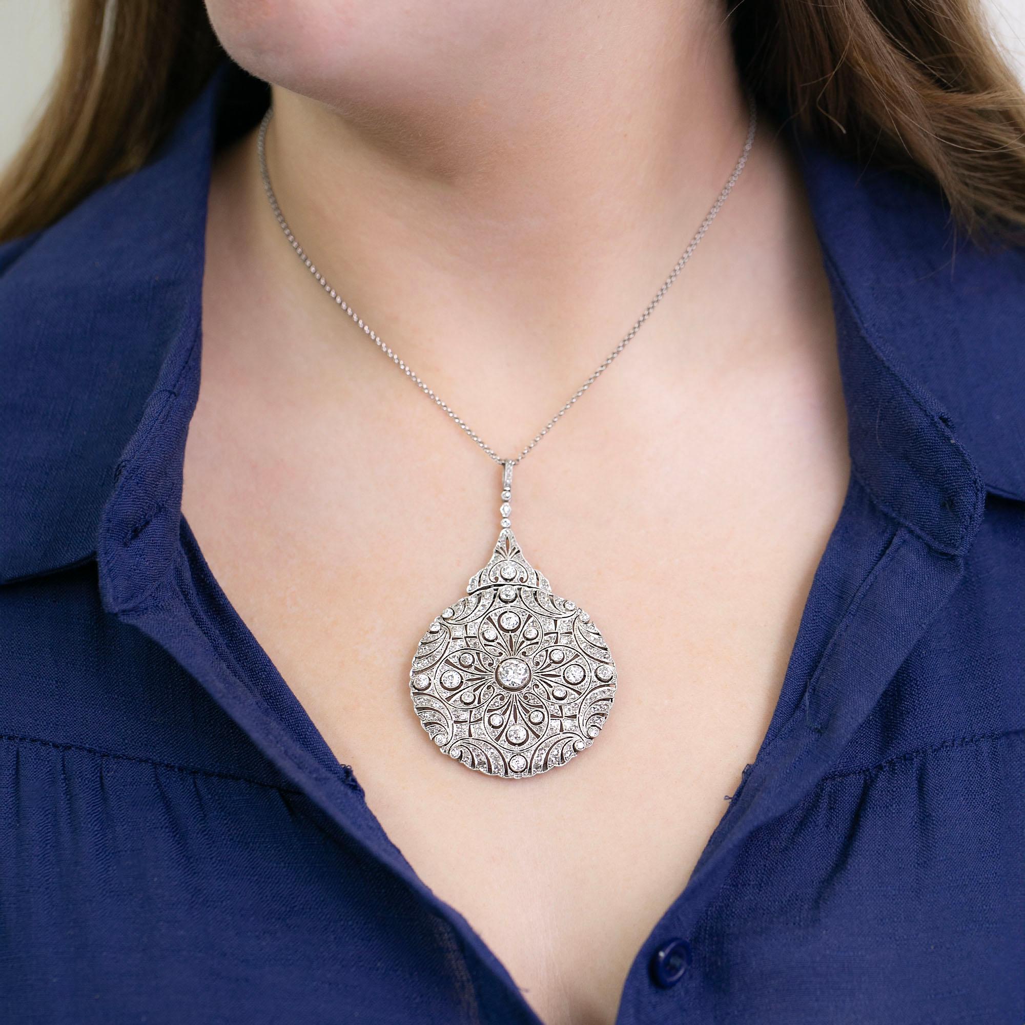 Il s'agit d'un superbe collier de l'époque de la Belle Époque. Réalisé à la main en platine avec des montures percées et mille grains, ce pendentif circulaire à la coulisse élaborée est orné de diamants de taille transitionnelle et rose. Il est