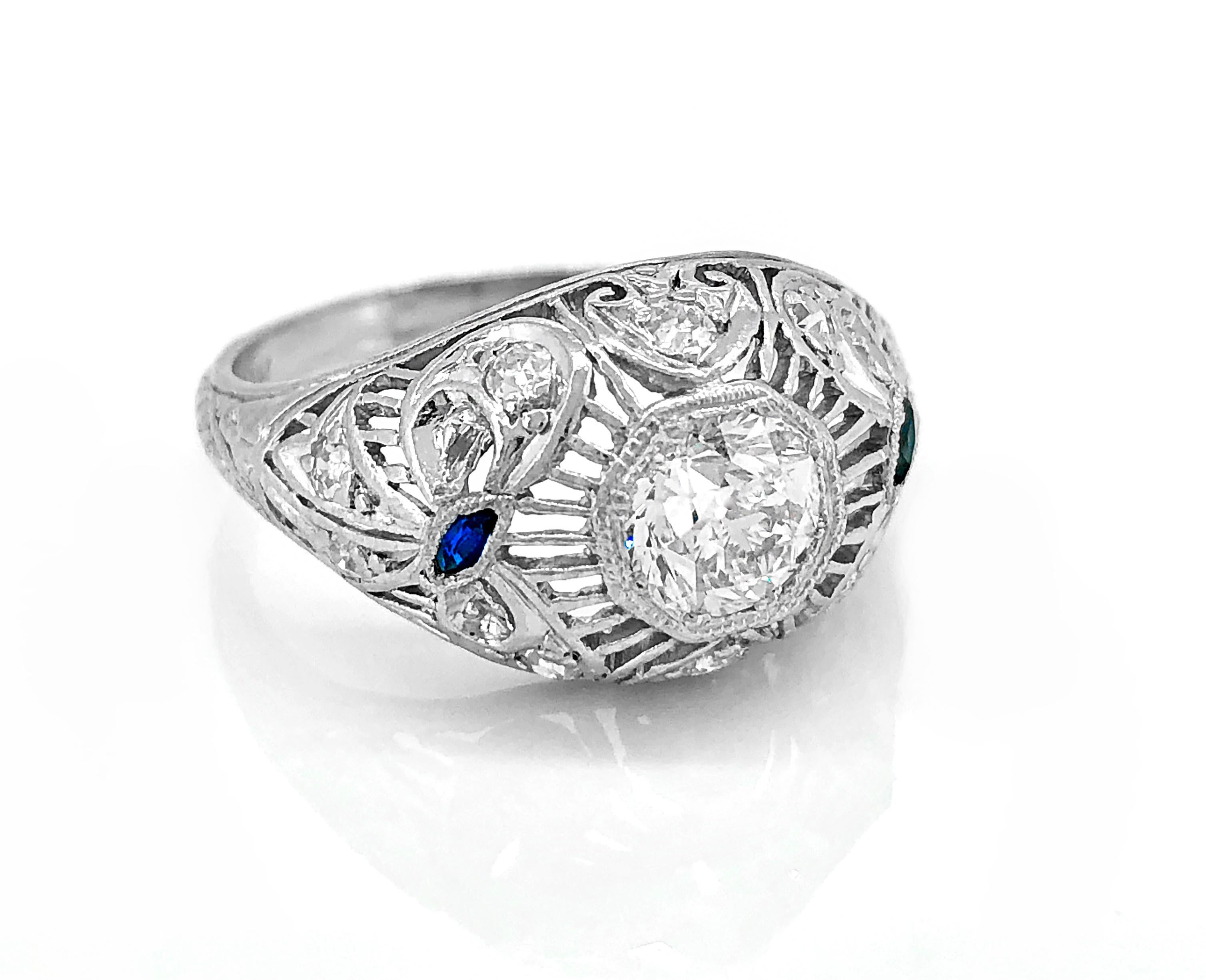 Tiny sapphires accent the shoulders of this absolutely gorgeous Belle Epoque/Edwardian platinum antique engagement ring! It is further enhanced by numerous small diamond melee and delicate engraving. The fiery .70ct. apx. VS2 clarity and I-J color