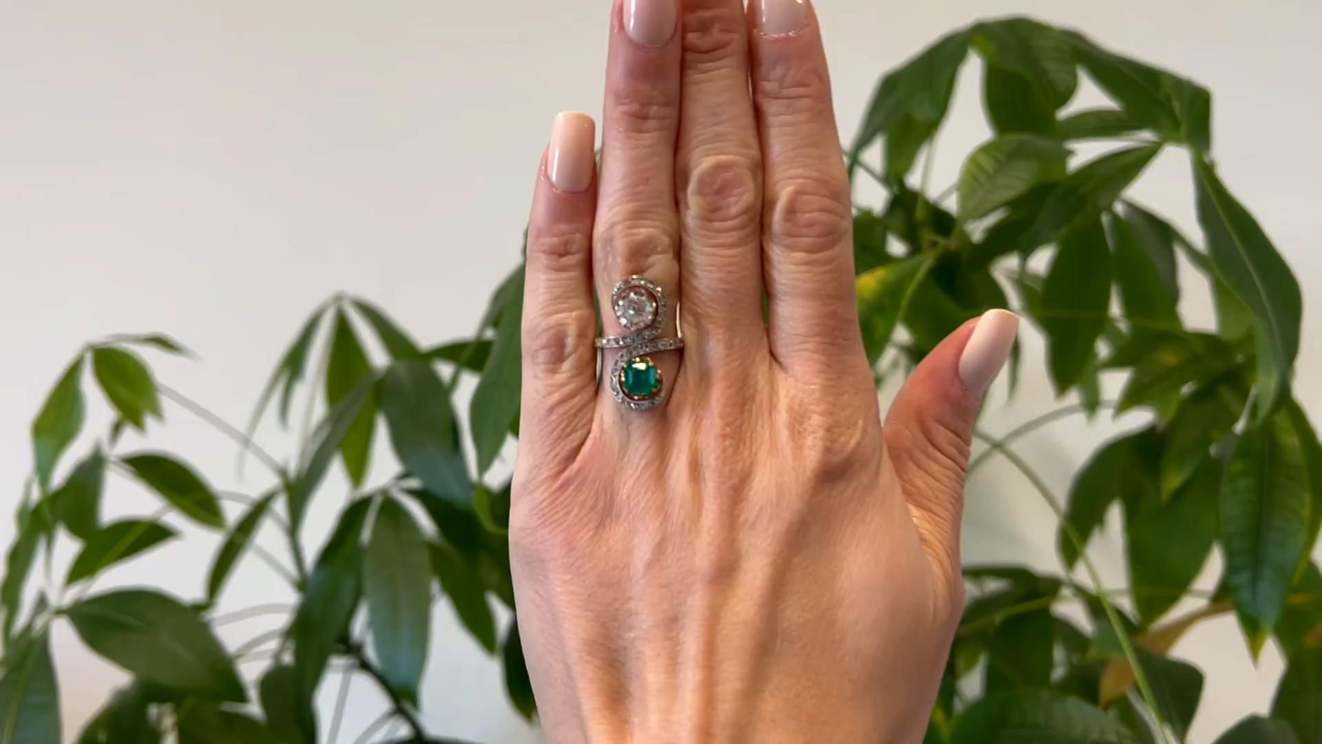 One Belle Époque French Emerald and Diamond 18k Yellow Gold Platinum Toi et Moi Ring. Featuring one old European cut diamond weighing approximately 1.45 carats, graded H color, VS2 clarity, and one octagonal step cut emerald weighing approximately
