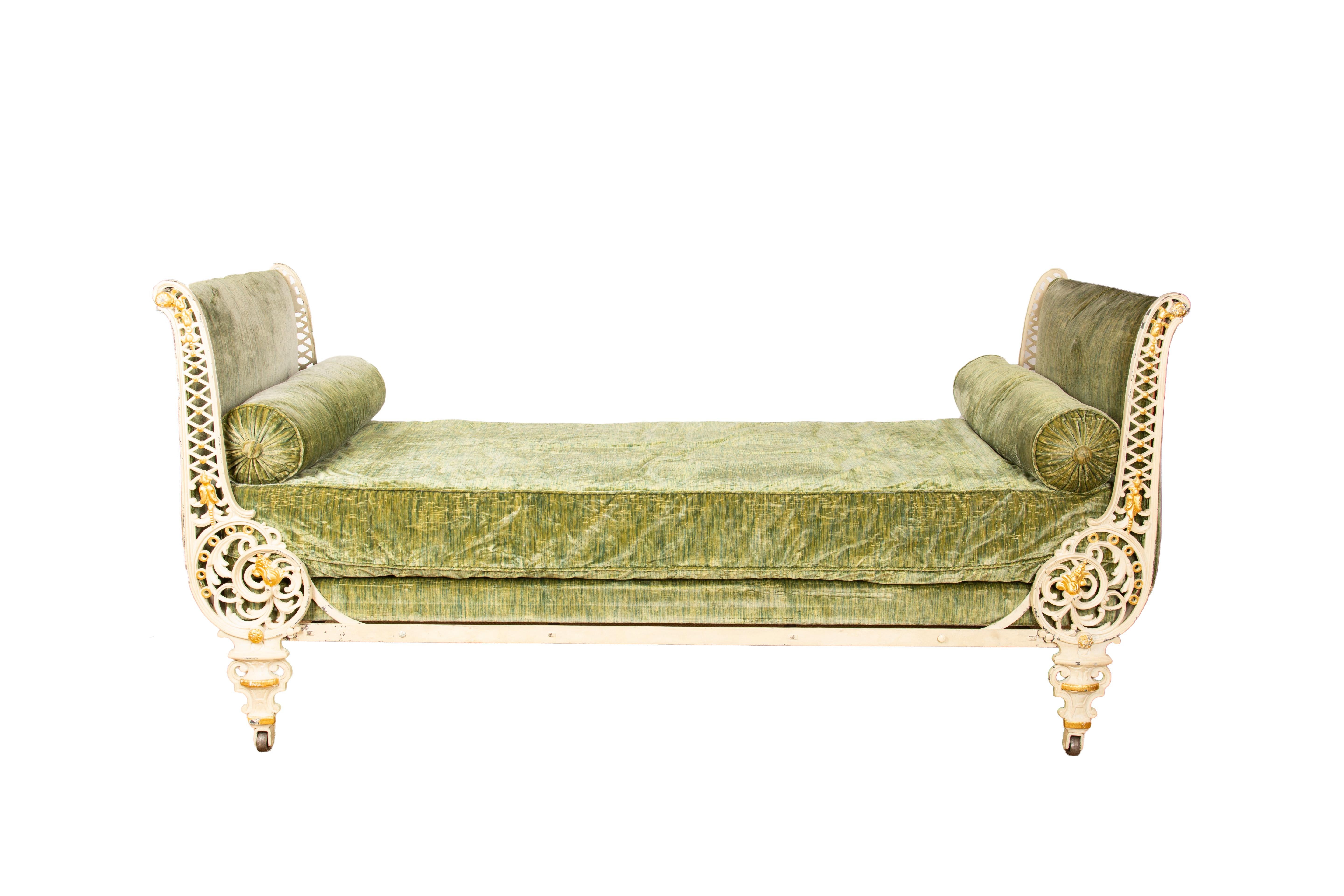 A charming 19th-century French cast iron daybed, richly detailed and full of antique character. The frame is elaborately cast with scrollwork, lattice, and foliate motifs, highlighted with hand-applied gold accents over a warm, timeworn