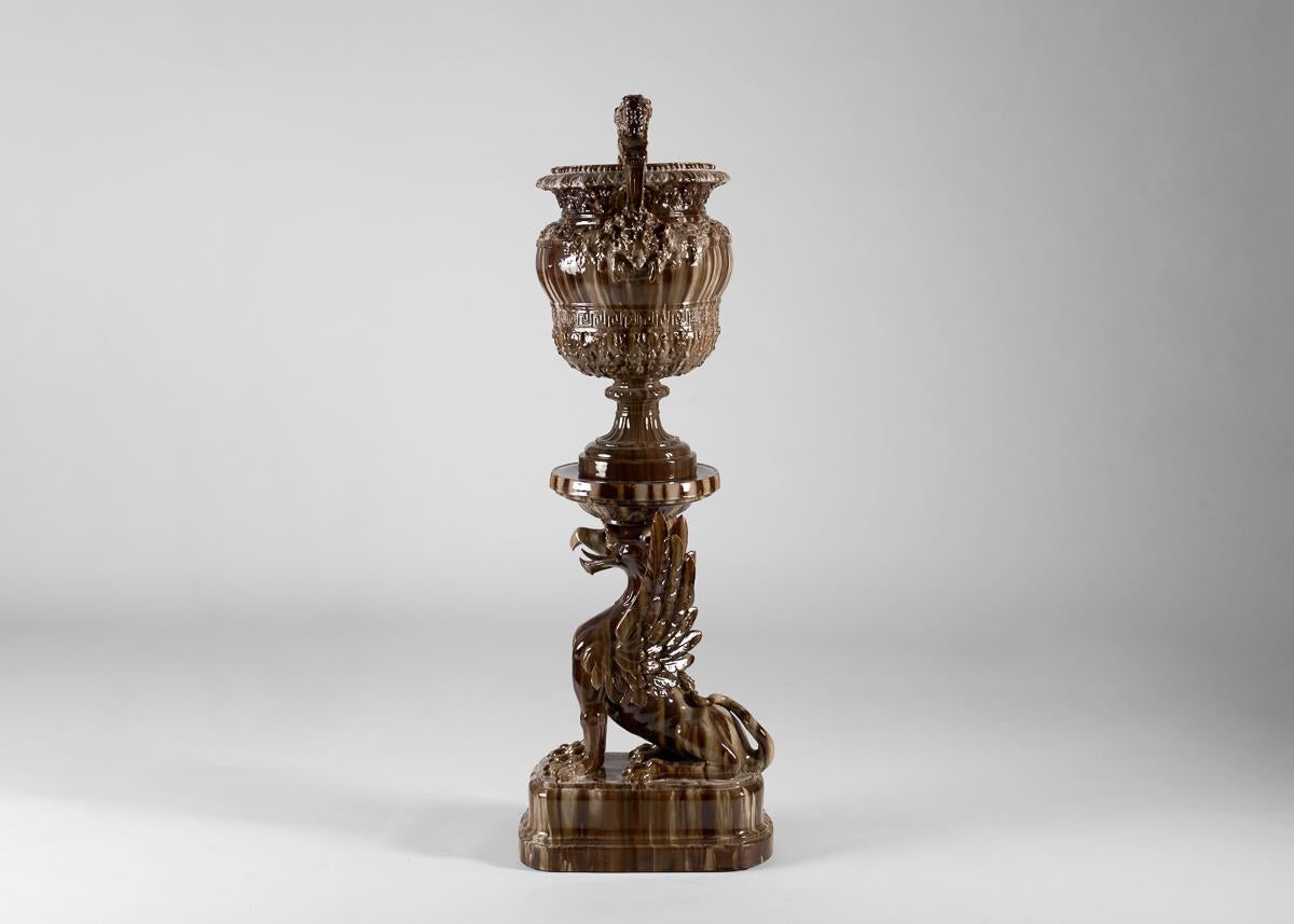 This elaborate Belle Époque urn stands atop the mythological beast, a winged griffin. Glazed in marbled browns it embodies both fierceness and grandeur, power and luxury.

Bibliography:
A la grande manufacture – Faïences d’art – Jérôme Massier fils