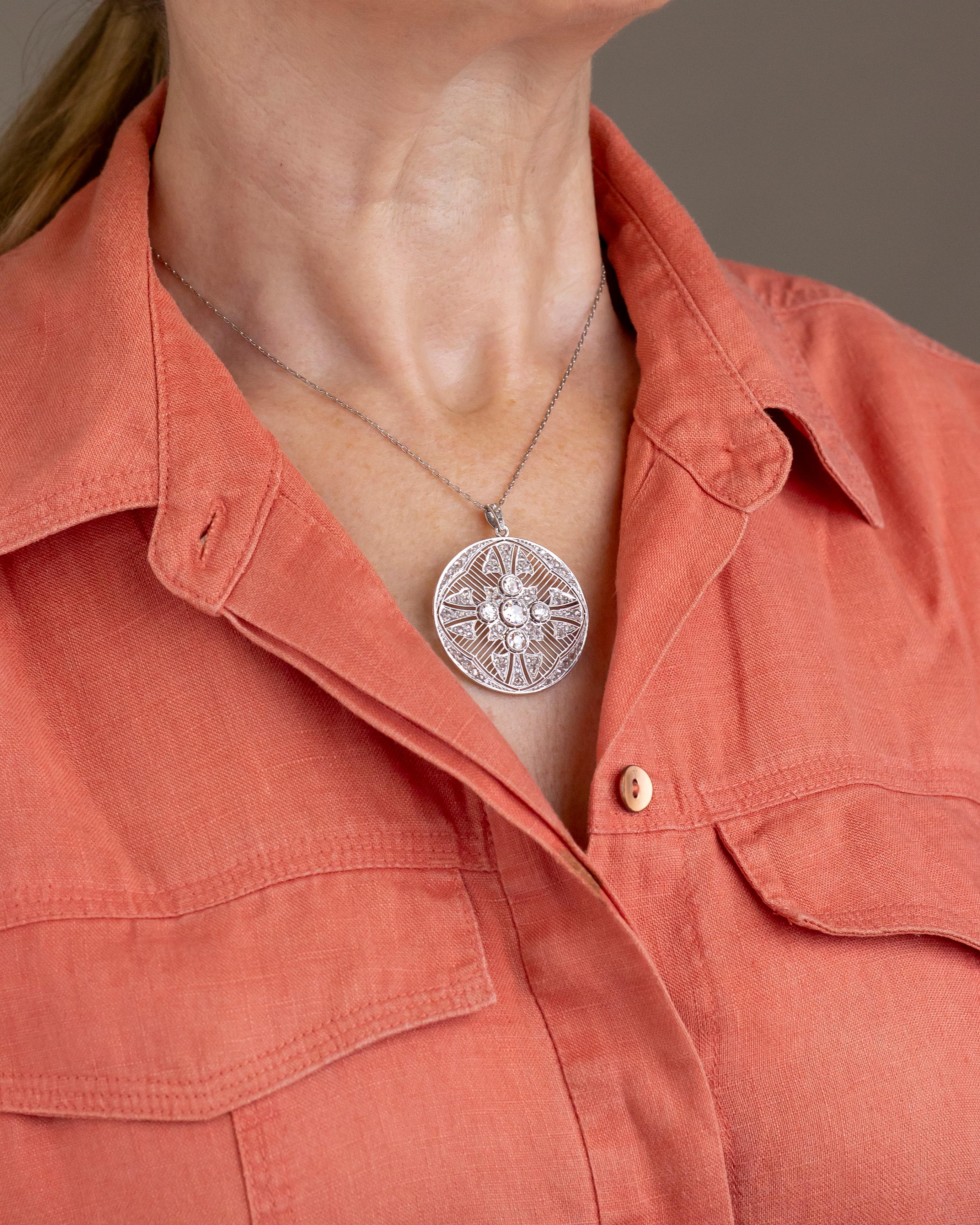 This beautifully handmade, platinum and diamond brooch pendant was crafted in the first part of the 20th Century and can be described as 'Belle Epoque'. The hand pierced platinum disc centres on a cross of Old European cut diamonds, the central