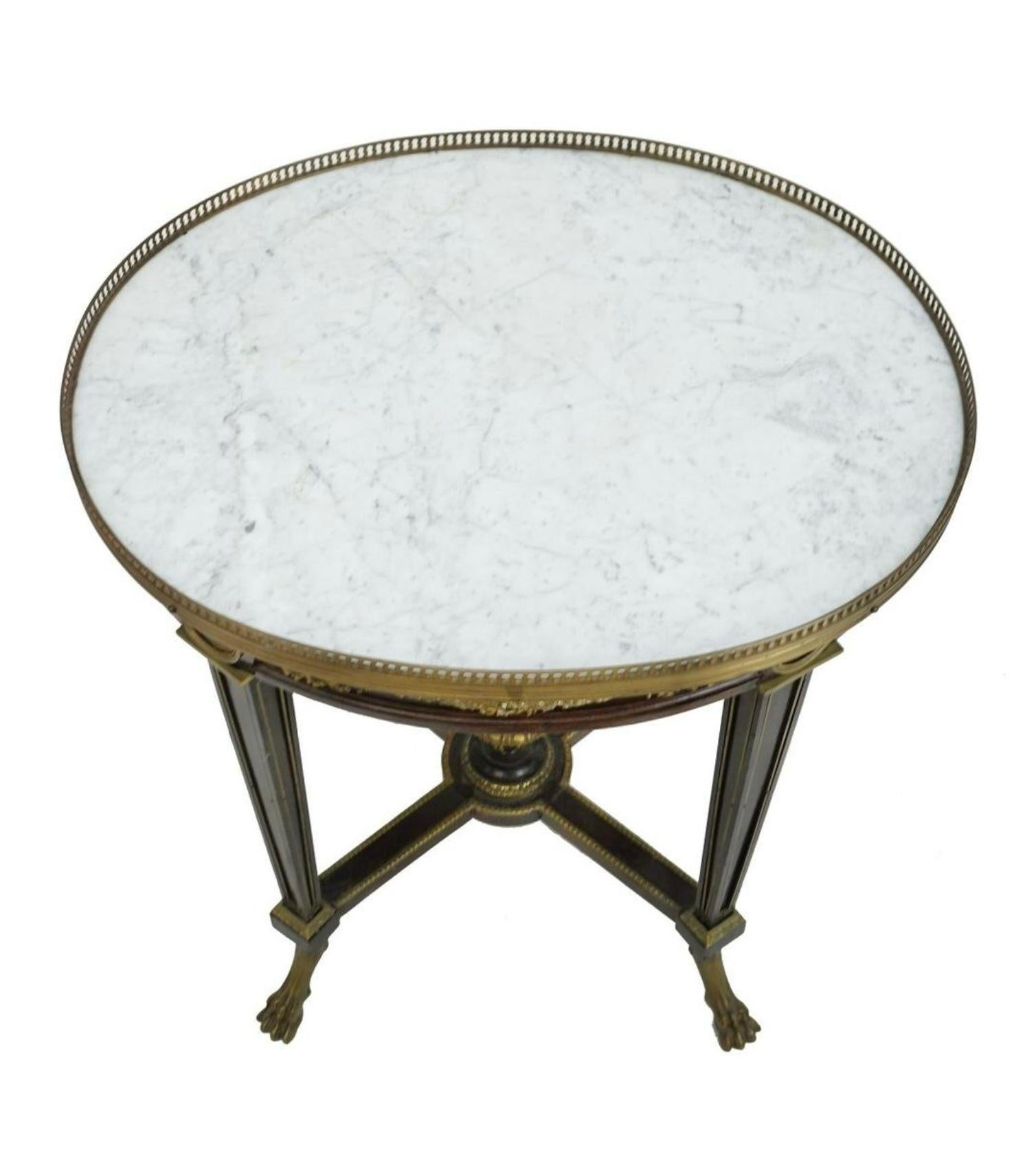 Belle Epoque Louis XVI Style Bronze Mounted Oval Side Table. Late 19 century, ornately designed with garlands and ribbons, figural scene medallions on apron, X-form stretcher with urn, and stands on fluted tapering legs with bronze lion paw feet.