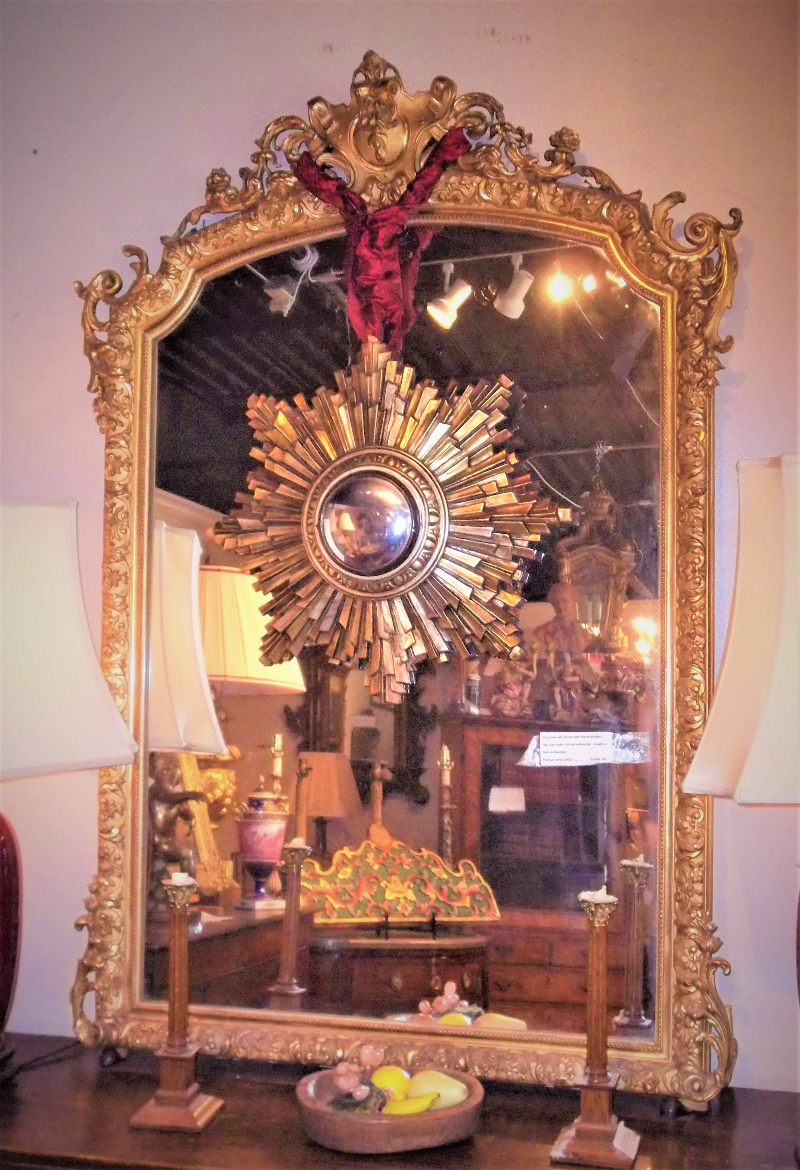 The mirror plate enclosed by gilded frame with floral and foliate scrolls. The crest with scrolling dolphins and cornucopia around a central cartouche. Each upper corner with niched curves.
Dust in crevices. Some red bole bleeding throughout...,