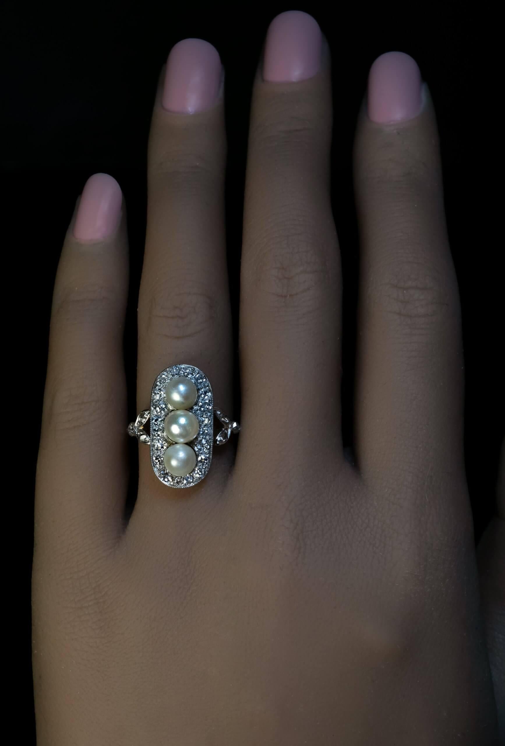 hacia 1910

Este elegante anillo antiguo está finamente elaborado en platino y oro amarillo de 18 quilates. Está engastado verticalmente con tres perlas (de 5 mm cada una) enmarcadas por diamantes talla brillante de mina vieja. Los hombros con