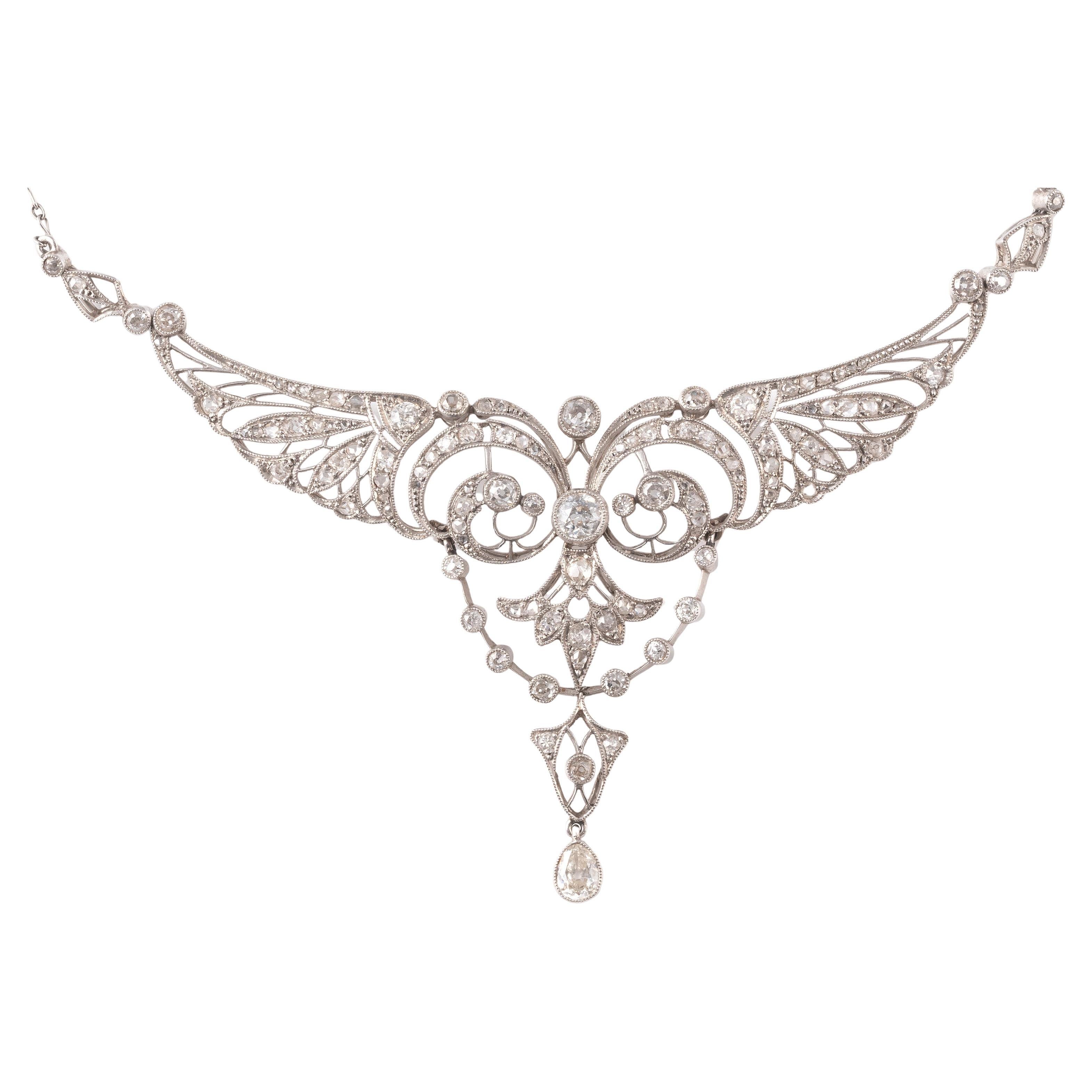 An Edwardian diamond-set necklace, circa 1910, designed as pierced stylised wings encasing millegrain-set diamond approximately 8ct scrolls and swags in platinum, on a fine-link platinum neck chain, pendant width 8cm, necklace length 36.5cm, in