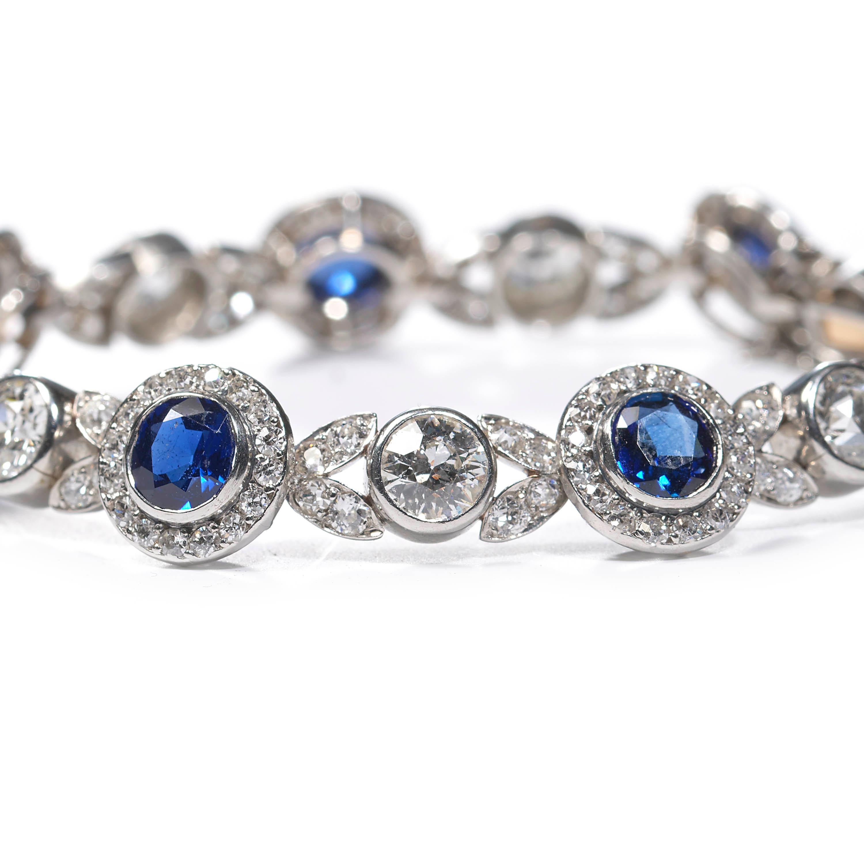 An antique Burmese sapphire and diamond bracelet, comprised of round Burmese sapphire and diamond clusters, connected by diamond-set leaf motifs, with a round old-cut diamond rub-over set in between each, all mounted in platinum. With a push-in