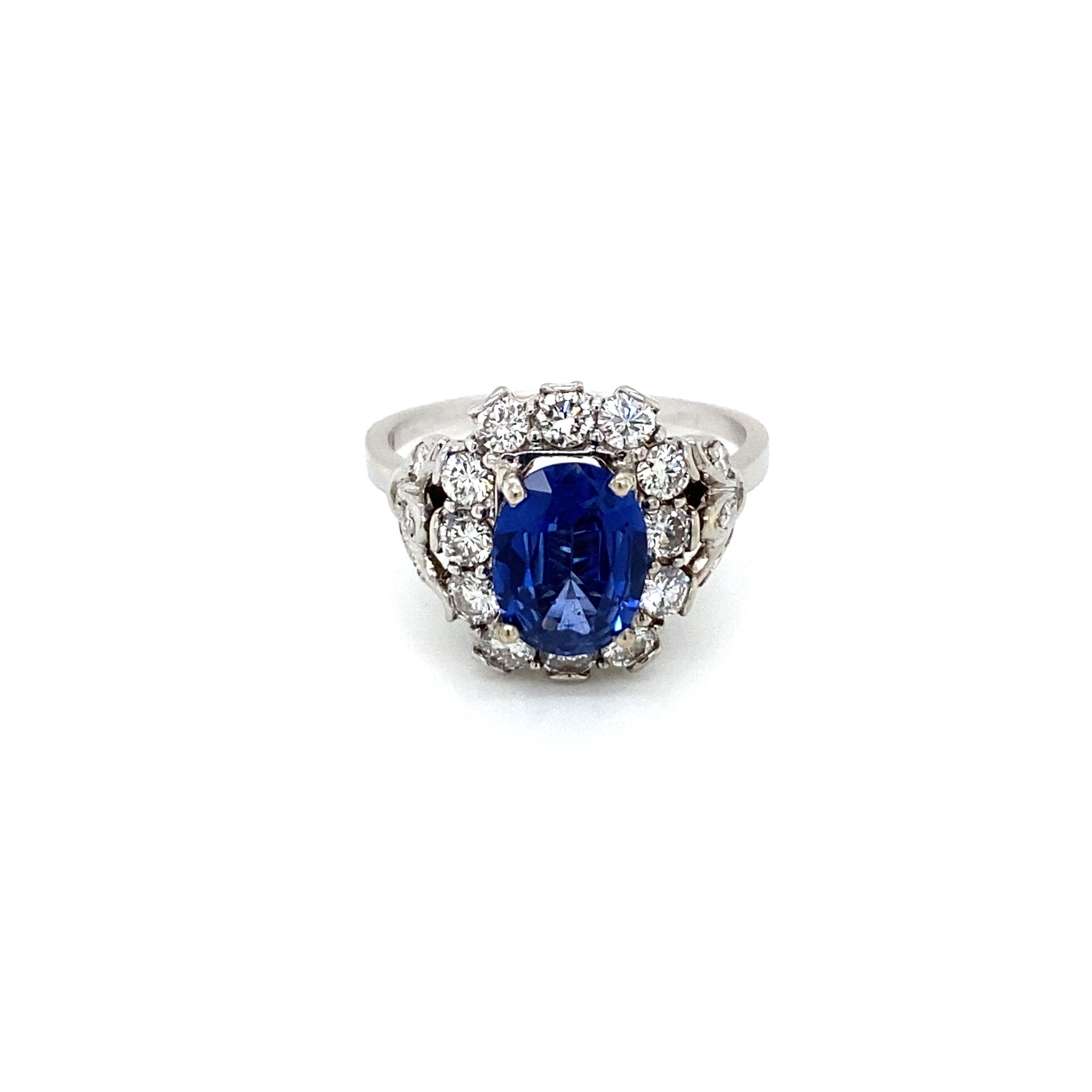 Beautiful18k white Gold, Blue Sapphire and Diamond cluster Ring, set in the center with an oval-cut Natural Sapphire weighing 1.72 carat and flanked by  sparkling old mine cut diamonds weighing .65 carat all together, graded  Color H clarity