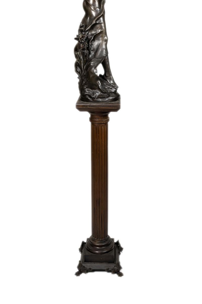 A Belle Époque bronze spelter sculpture titled “Queen of the Fields” signed by Auguste Moreau, featuring a graceful young woman clutching a bundle of wheat, mounted on a fluted column pedestal. 

Made in France in the late 19th century, this work is