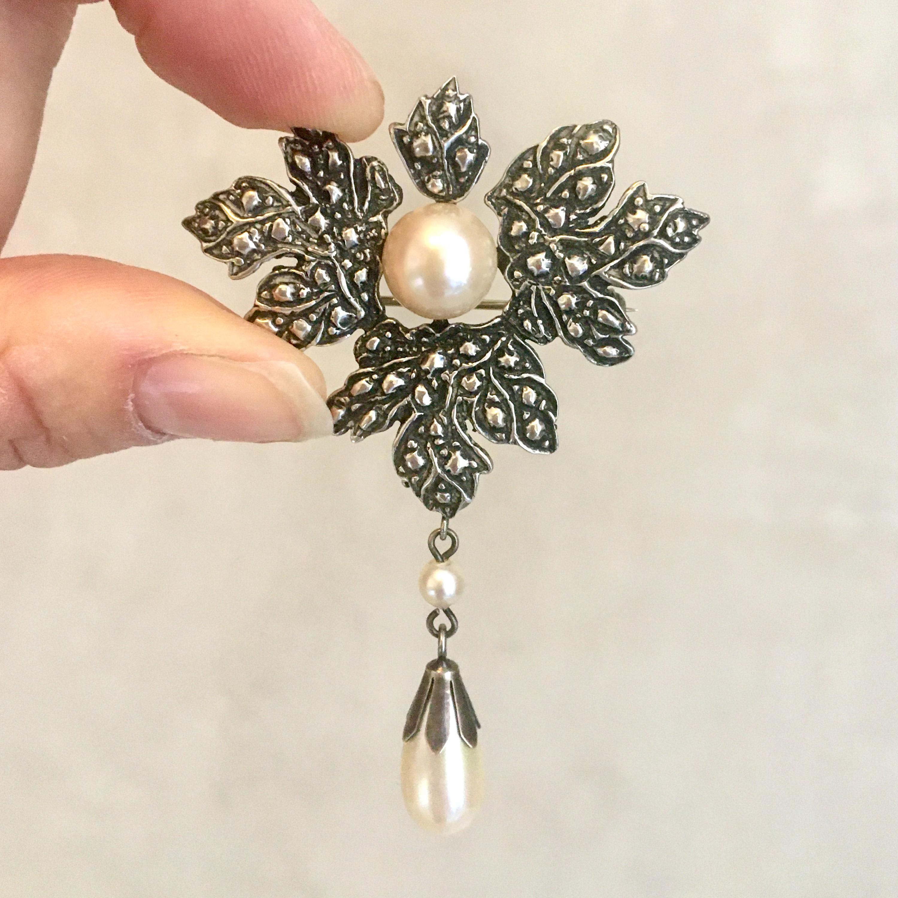 A Belle Epoque-style silver cultured pearl brooch. The silver is beautifully crafted in the shape of a maple leaf, leaves symbolize growth and letting go. The brooch consists of a center pearl, surrounded by a silver maple leaf and a pendant pearl.