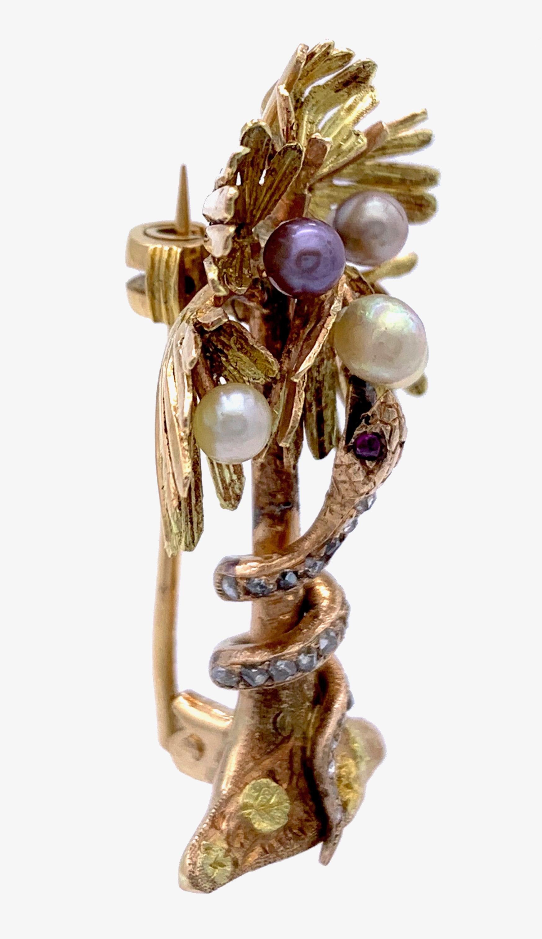 This wonderful piece of jewellery is made out of three different shades of 18k gold and shows a rose diamond set snake curling itself around the trunk of a Palm tree.  It's finely engraved head with rubys set eyes is looking up to the treetop which