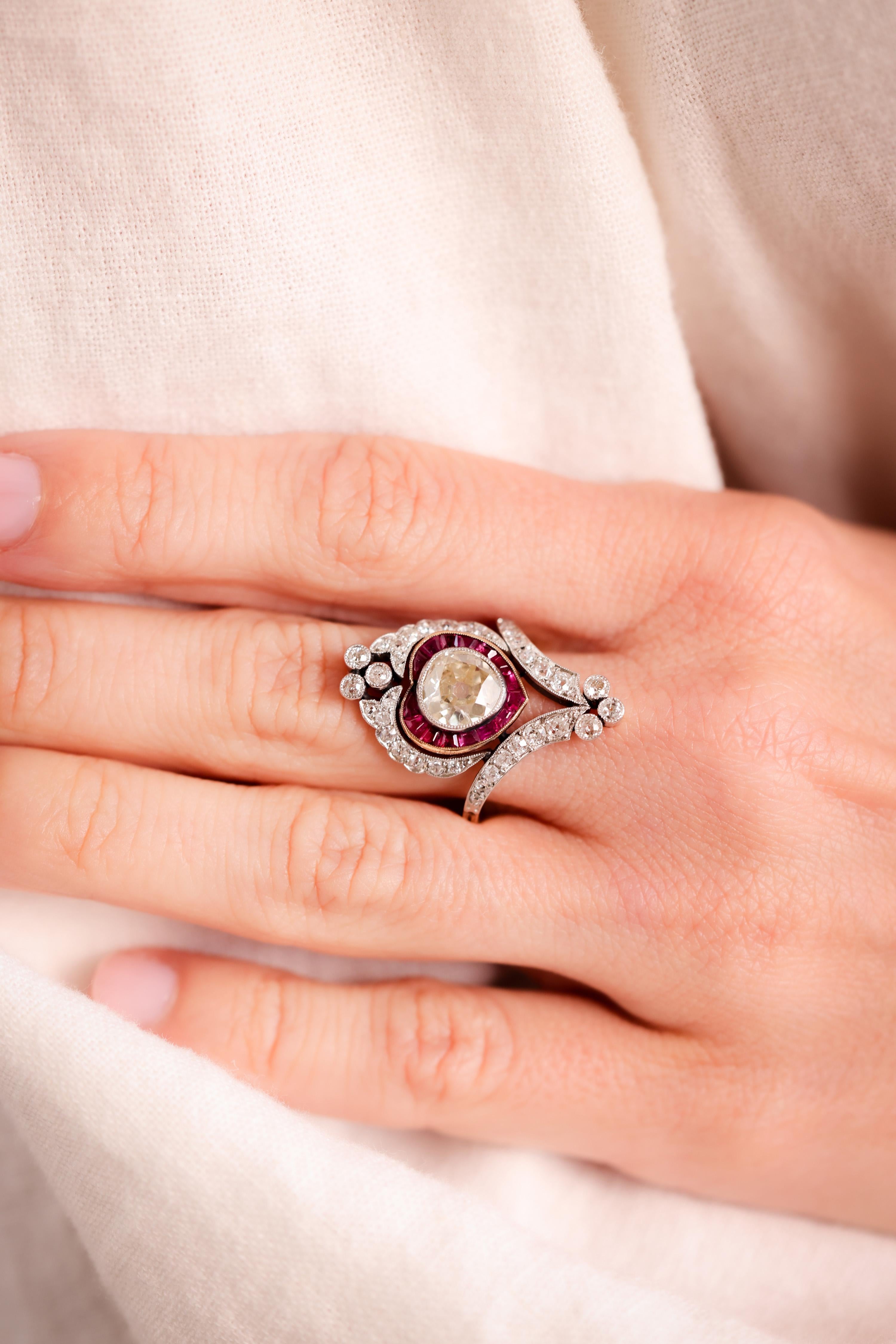 Center Stone: Diamond
Cut: Old Mine
Weight: 2.12 Carat 
Color: O-P
Clarity: SI
Accent Stone: 36 Diamonds
Cut: Old Mine
Weight: Approximately 1.5 Carats
Color: H
Clarity: SI
Accent Stone: 15 Rubies
Cut: Trapezoid
Weight: Approximately 0.8