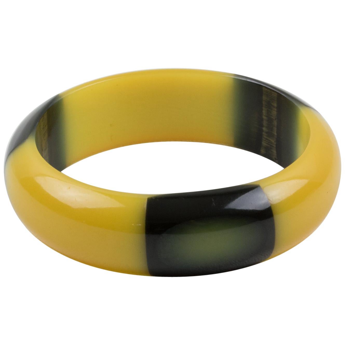 This piece is an outstanding Belle Kogan Bakelite elongated inlay dot bracelet bangle. The dots are set with a true licorice black surrounding color, in a light banana yellow color, and appear three times around the bangle. The bracelet has a domed