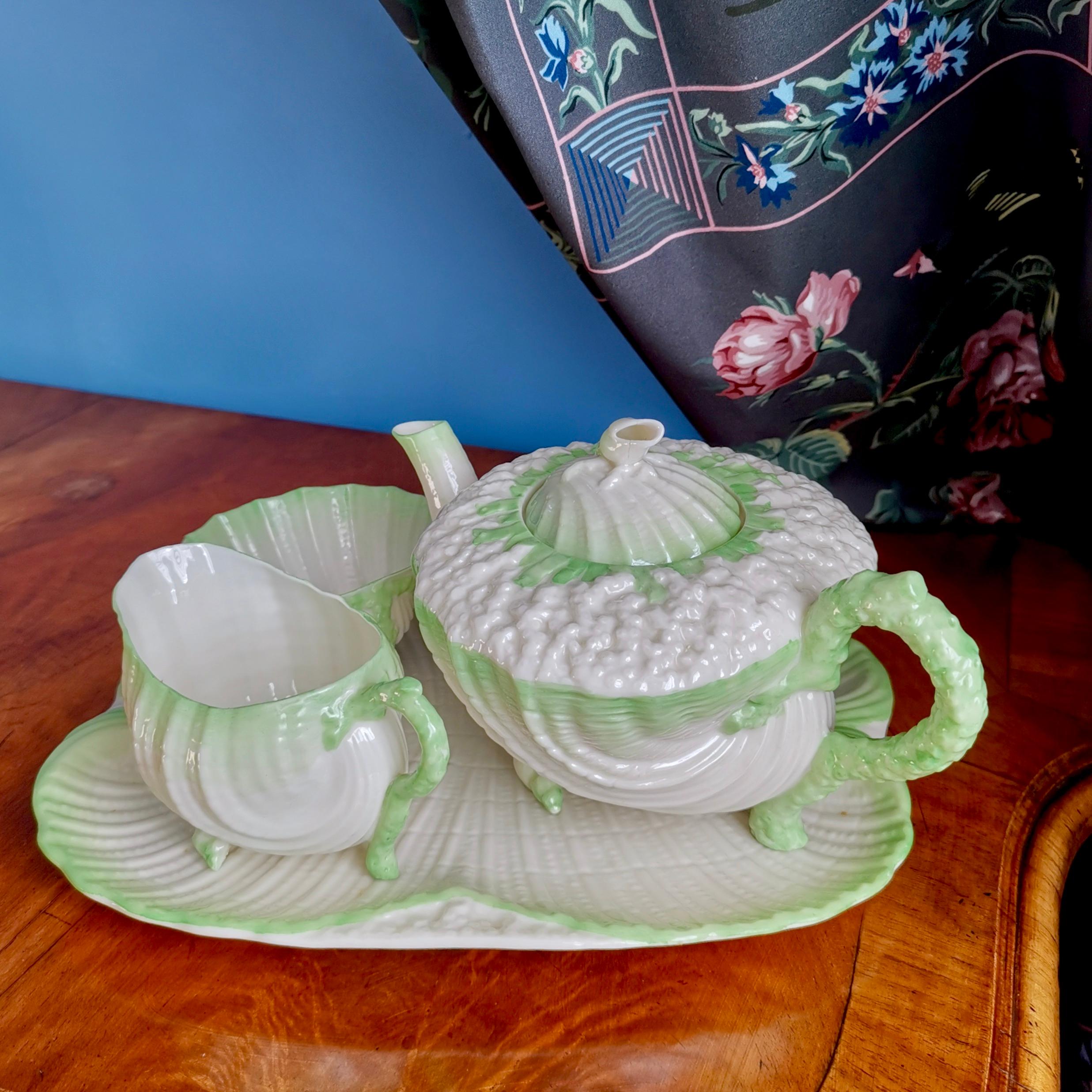 This is a rare and gorgeous Belleek cabaret teapot set in the green Neptune design, consisting of a teapot, a milk jug and a sugar basin, all placed on a small tray. All items carry the 2nd black mark, which was used between 1891 and 1926.

If you