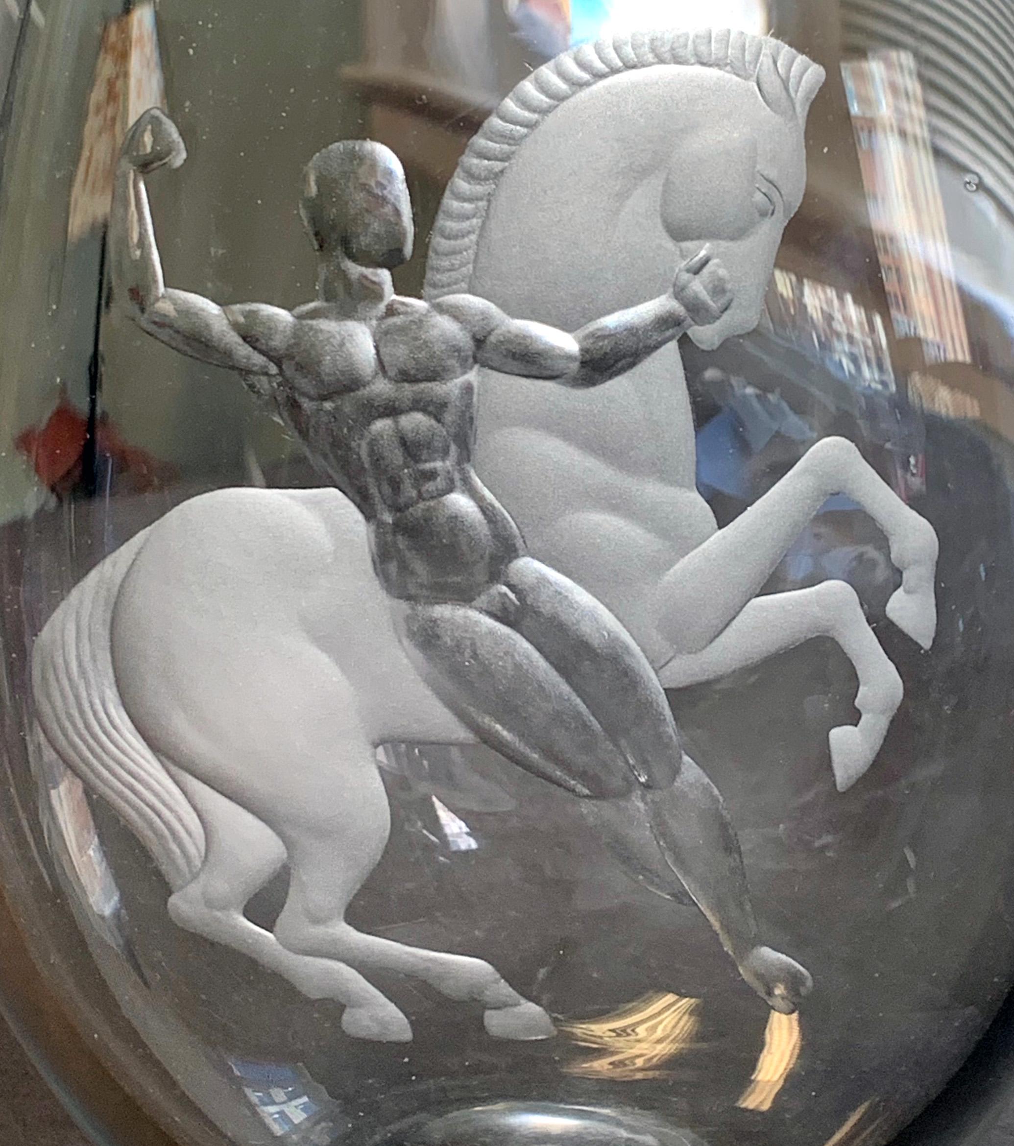 Ce rare et remarquable vase Art déco - créé par l'un des maîtres de l'art du verre gravé dans les années 1930 - représente Bellérophon apprivoisant le personnage sauvage et volant de Pégase, après l'avoir attrapé au lasso après que la créature se