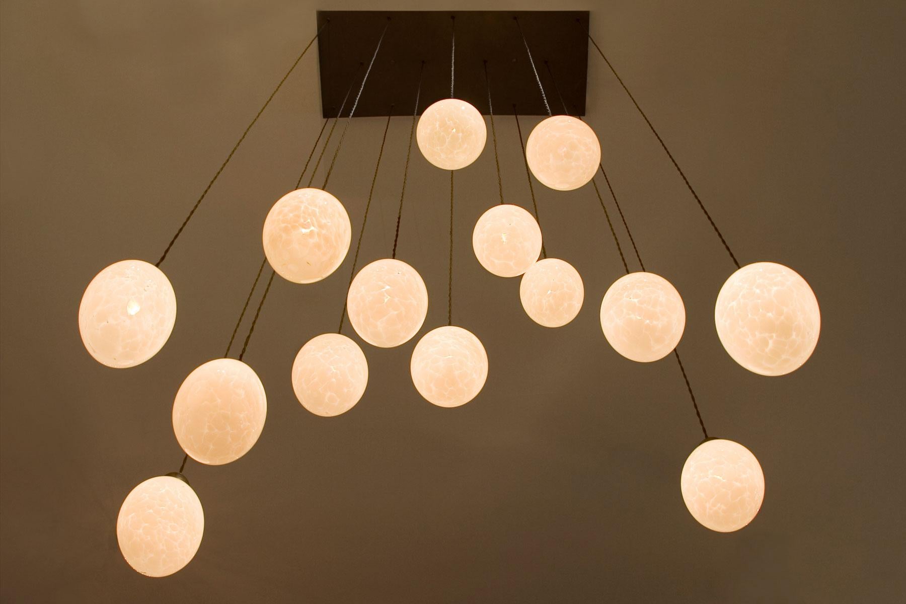 14 hand blown globes suspended from a rectangular bronze canopy. The braided silk wires can be shortened on site if needed. Fixture uses 14 candelabra base bulbs. Max wattage 40 each socket.