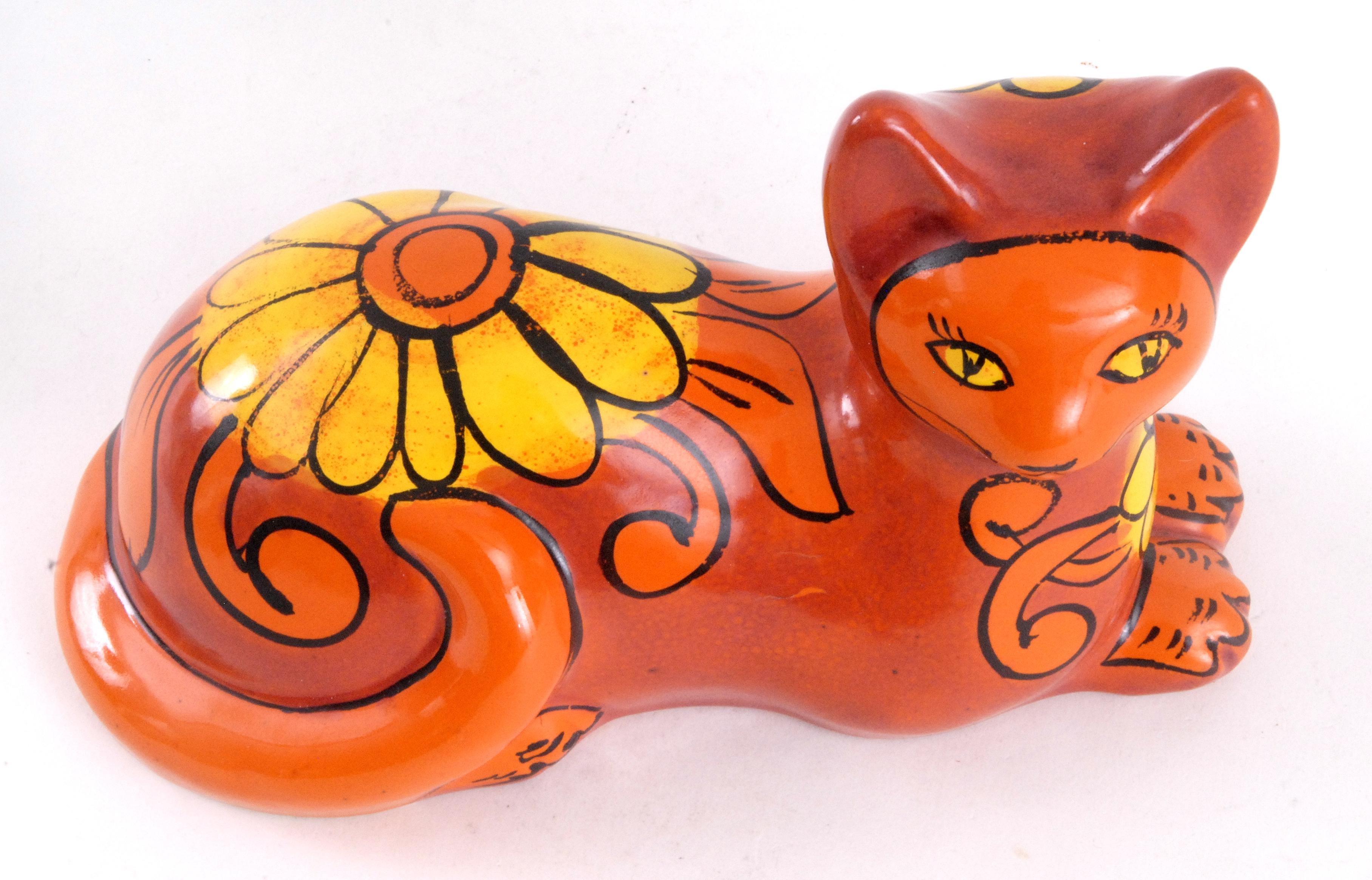An orange glazed cat decorated with a large sunflower on its back. Incised mark to base. Facial details, feet and tail painted with a black glazed line.