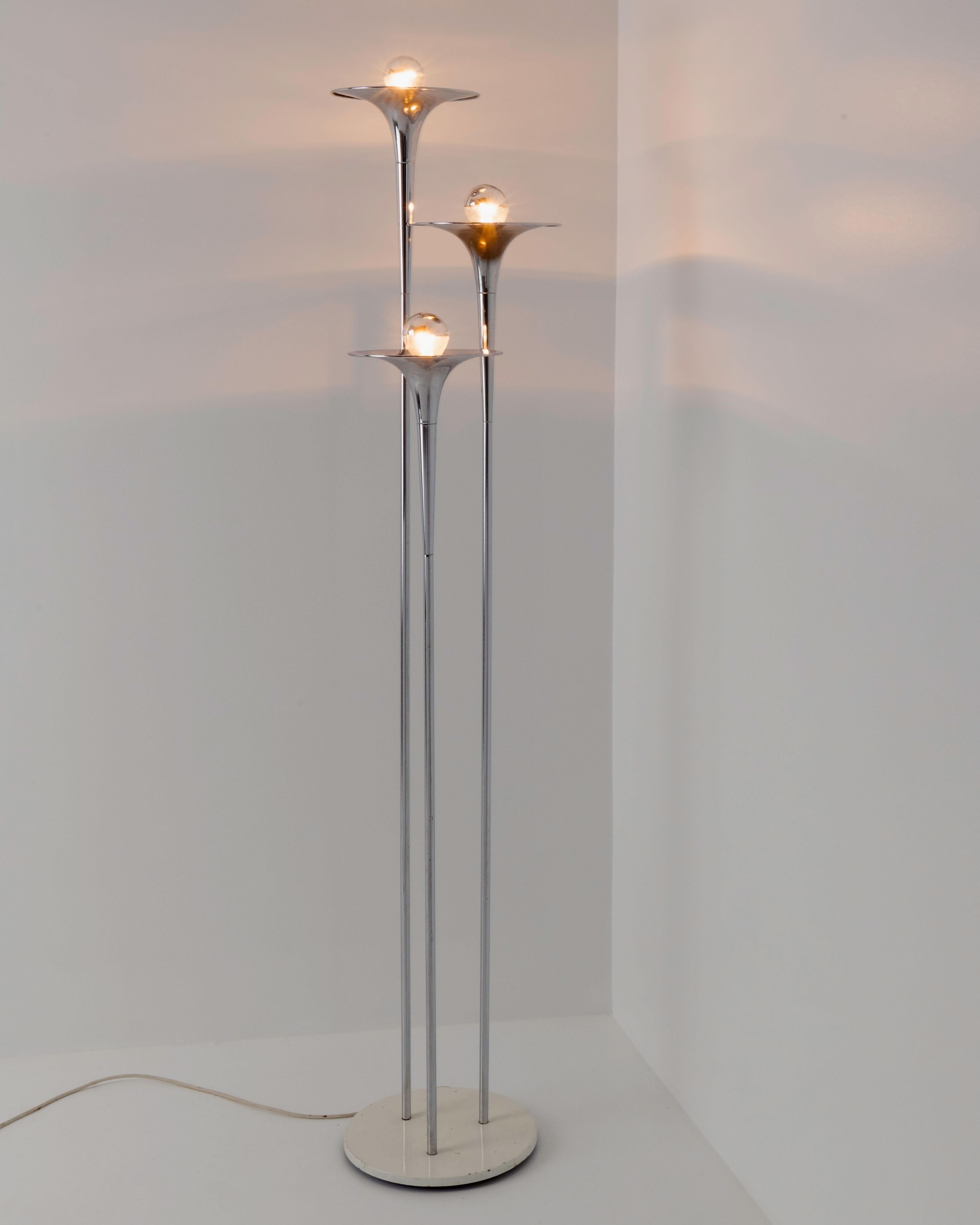 The triple trumpet lamp consists out of three chromed trumpet-shaped sconces. Each sconce is placed at a different height, all resting on a circular base.
The lamp was designed by American industrial designer, Tony Paul, who specialized in lighting.