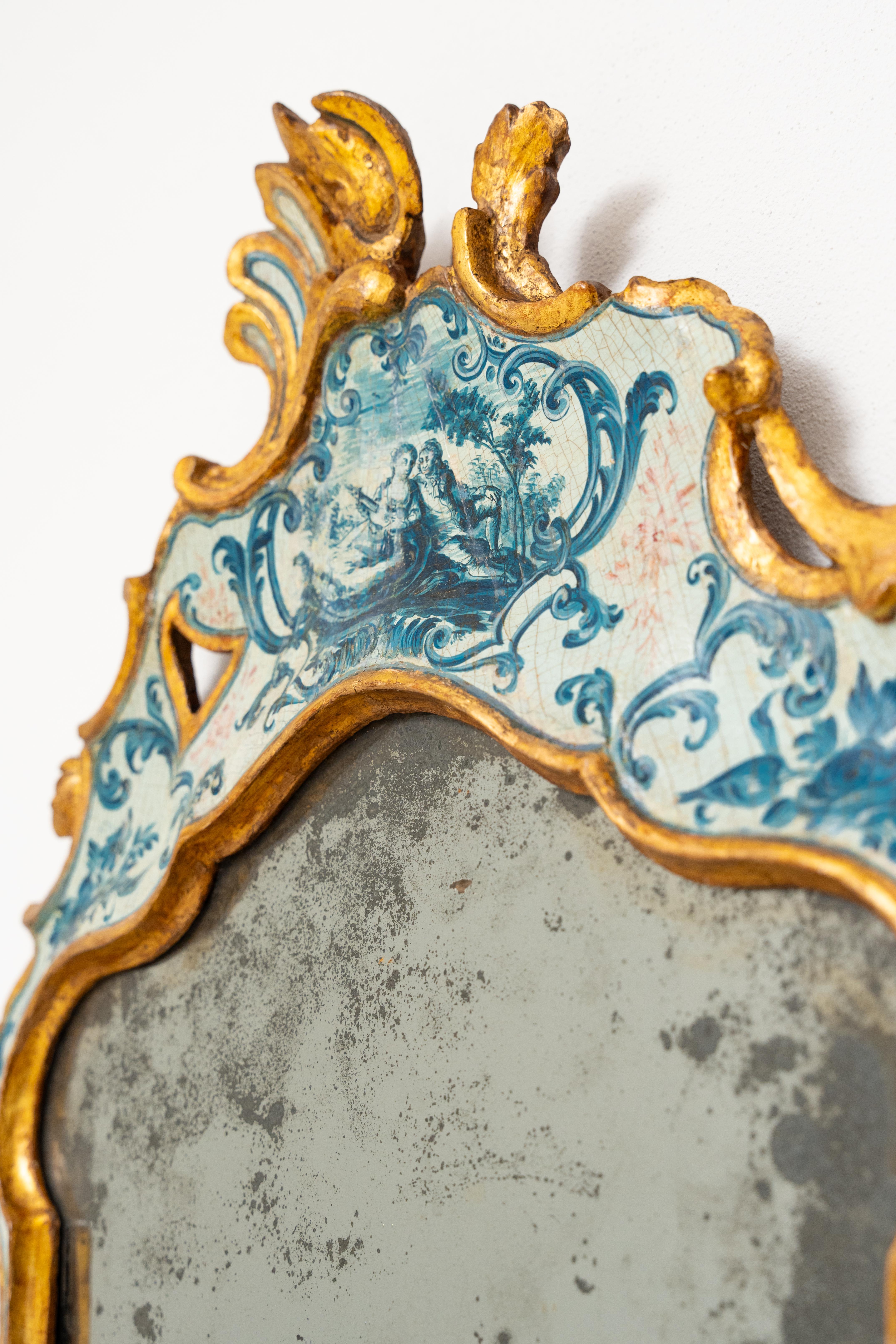 This beautiful little mirror was made in Venice around 1750. It features a painted, lacquered and gilded pine (softwood) wood frame. The frame is fully shaped. At the top we find a figure of a lady and knight within a bucolic setting and all around