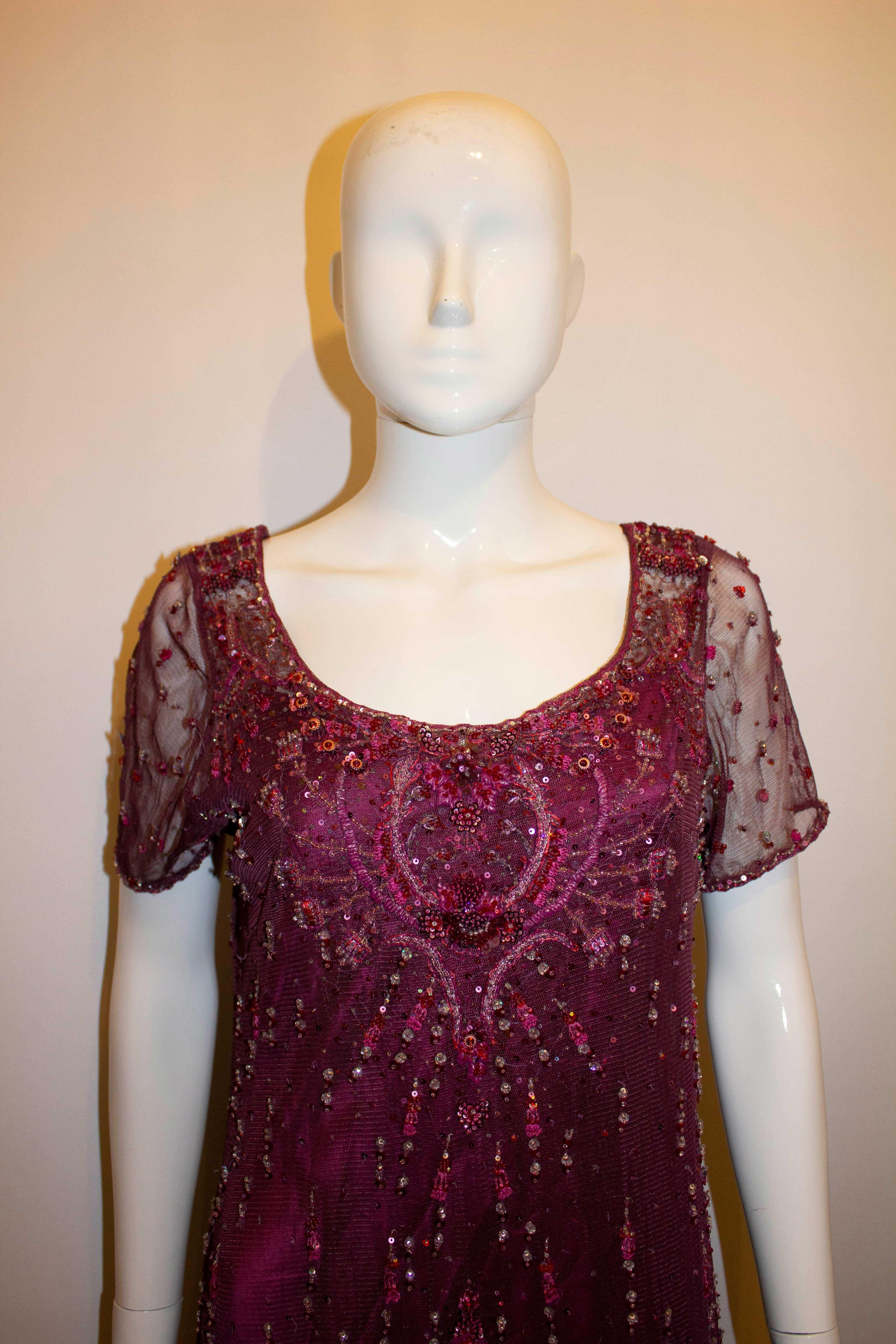 A head turning and easy to wear evening gown by Bellville Sassoon /Lorcan Mullany. The outer fabric is net with bead and sequin detail. The lining / slip dress is in plum silk. The dress has a button back opening and short sleaves. UK size 14,