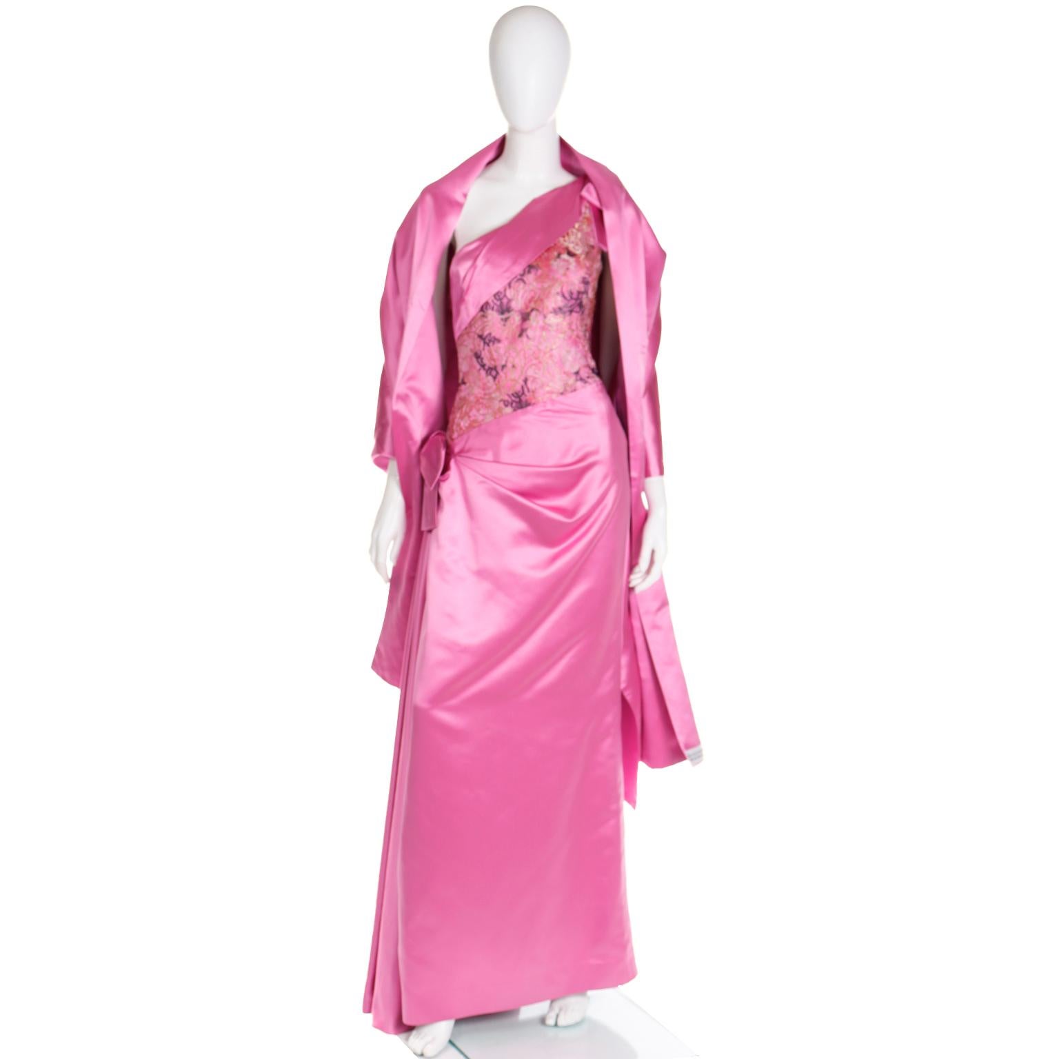 This is an elegant vintage 1990's pink satin evening gown with a matching pink satin wrap for chilly nights. This gorgeous one shoulder dress is beautifully draped and features gorgeous floral mesh lace on the bodice. The draping at the hip is