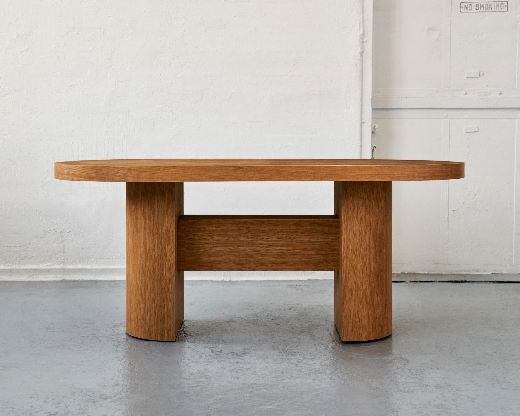 A custom dining table drawing inspiration from both the Brutalist and Memphis design movements. The track dining table is comprised of premium quality curved plywood and real wood veneer. It features an oval top set on two half-round pedestals
