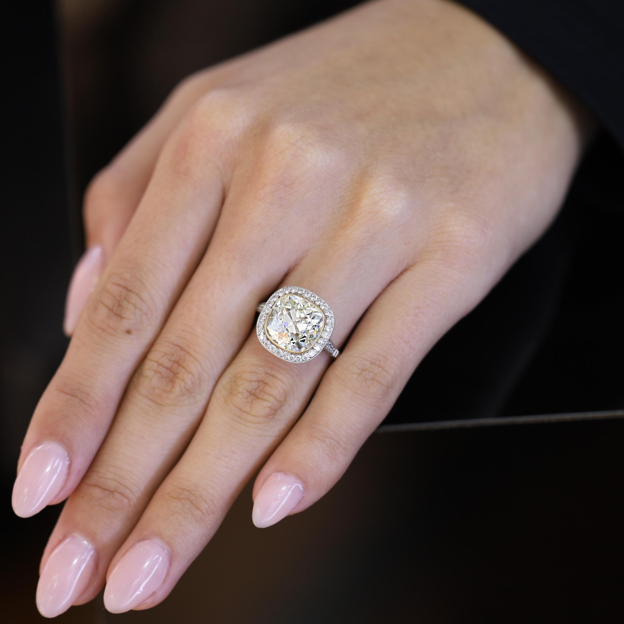 Centrato su un enorme diamante antico da 5,51 carati, questo anello di fidanzamento di ispirazione Art Deco è stato realizzato a mano in platino utilizzando le gemme originali di un cimelio amato ma usurato. Le ampie sfaccettature e l'alta corona di