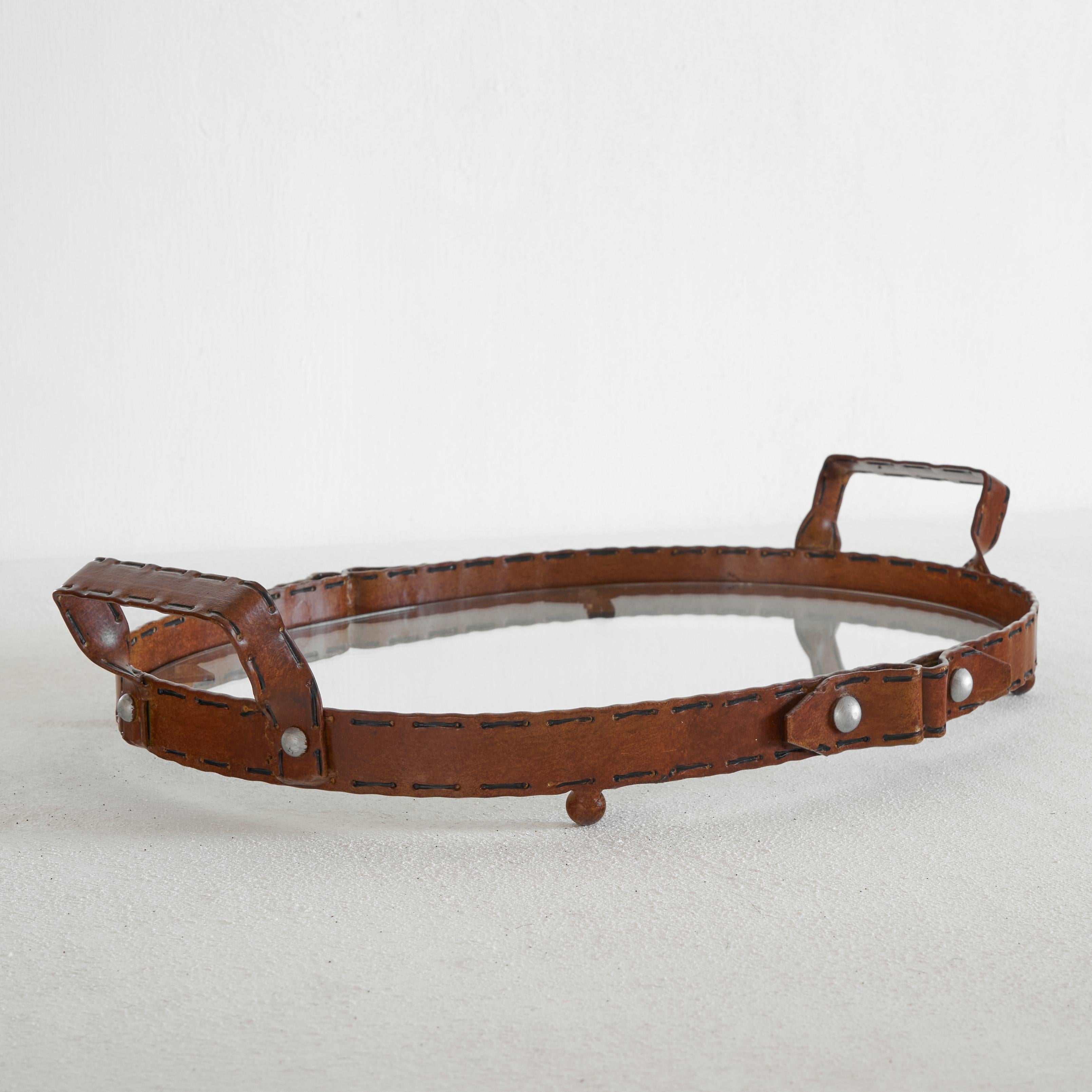 Belt-like serving tray in metal and glass.

Very unusual piece in metal and glass. This serving tray is made out of metal, but looks like it is made out of a leather belt. The cognac colored leather-like appearance of the metal is skillfully done