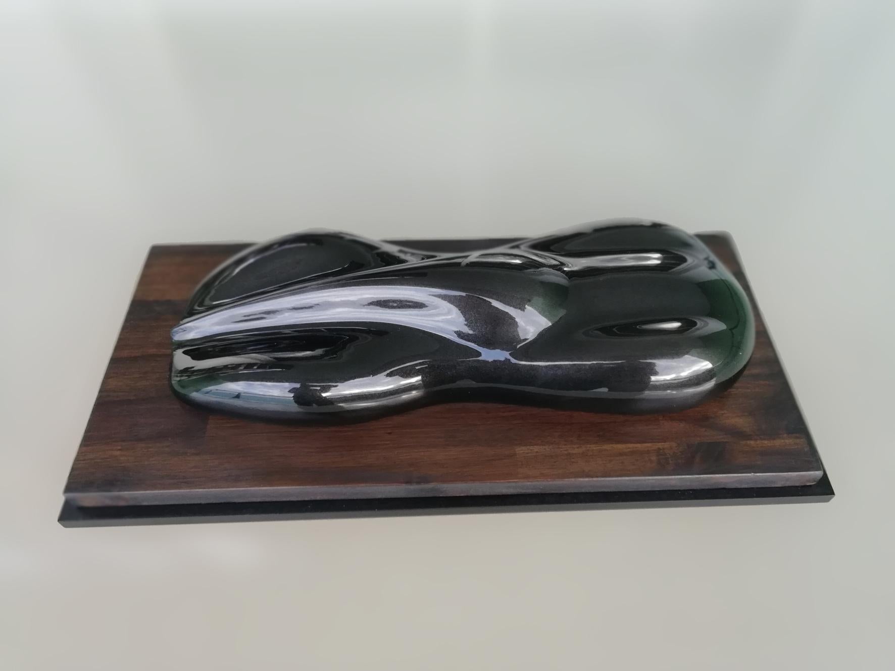 A dark green lacquered and varnished plaster model of a racing car.
On a lacquered rectangular wood base.

Belzoni finds inspiration in the legendary racing cars of the 1950s and the 1960s.
His elegant sculptures epitomize the spirit of a