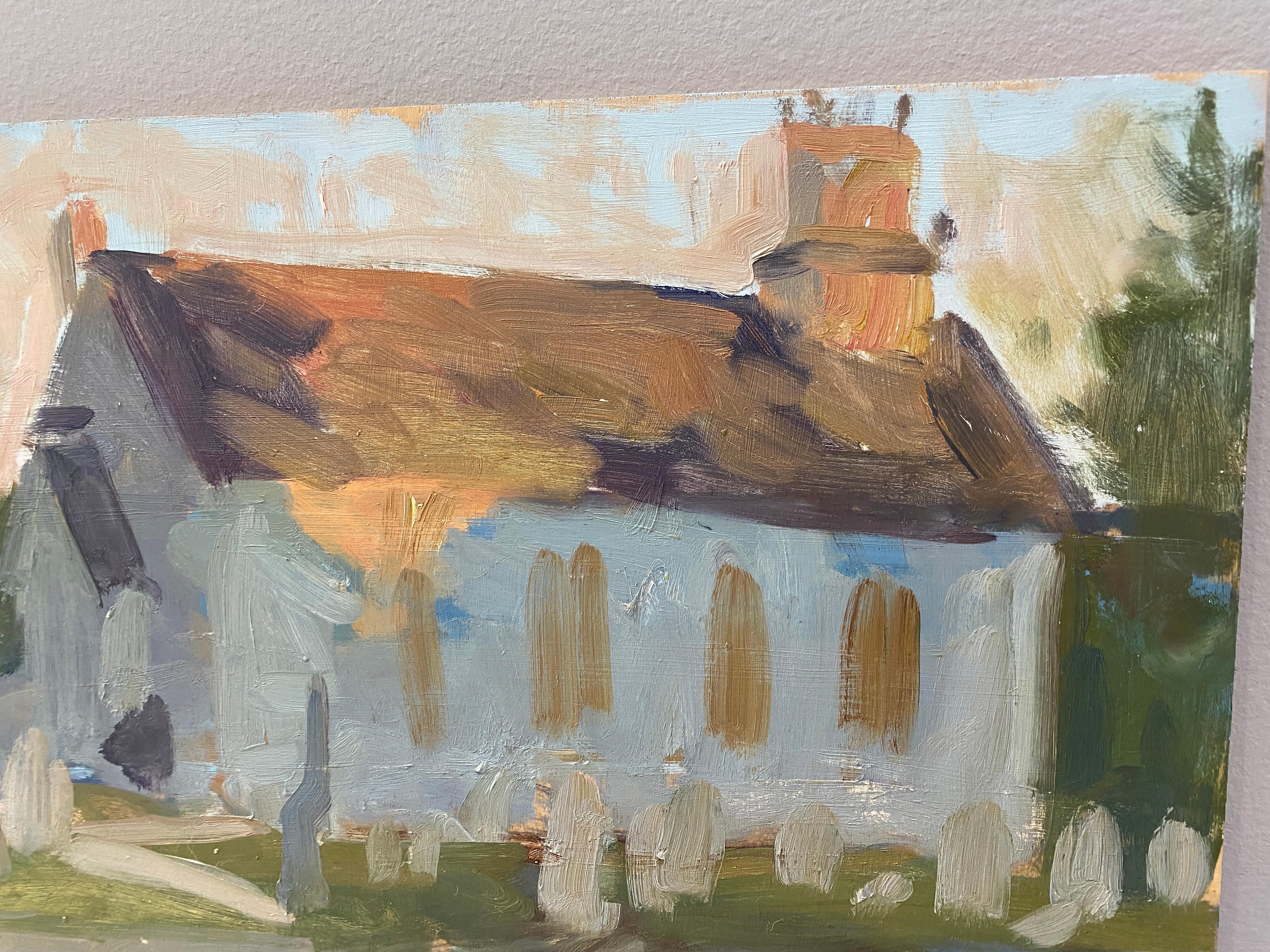A small scale oil on wood panel sketch of a white church, painted from life. A blue sky is dusted with an orange hue, signifying the end of the day. Orange light hits the roof of the church, and leaves the rest of the structure in shadow. A cretara