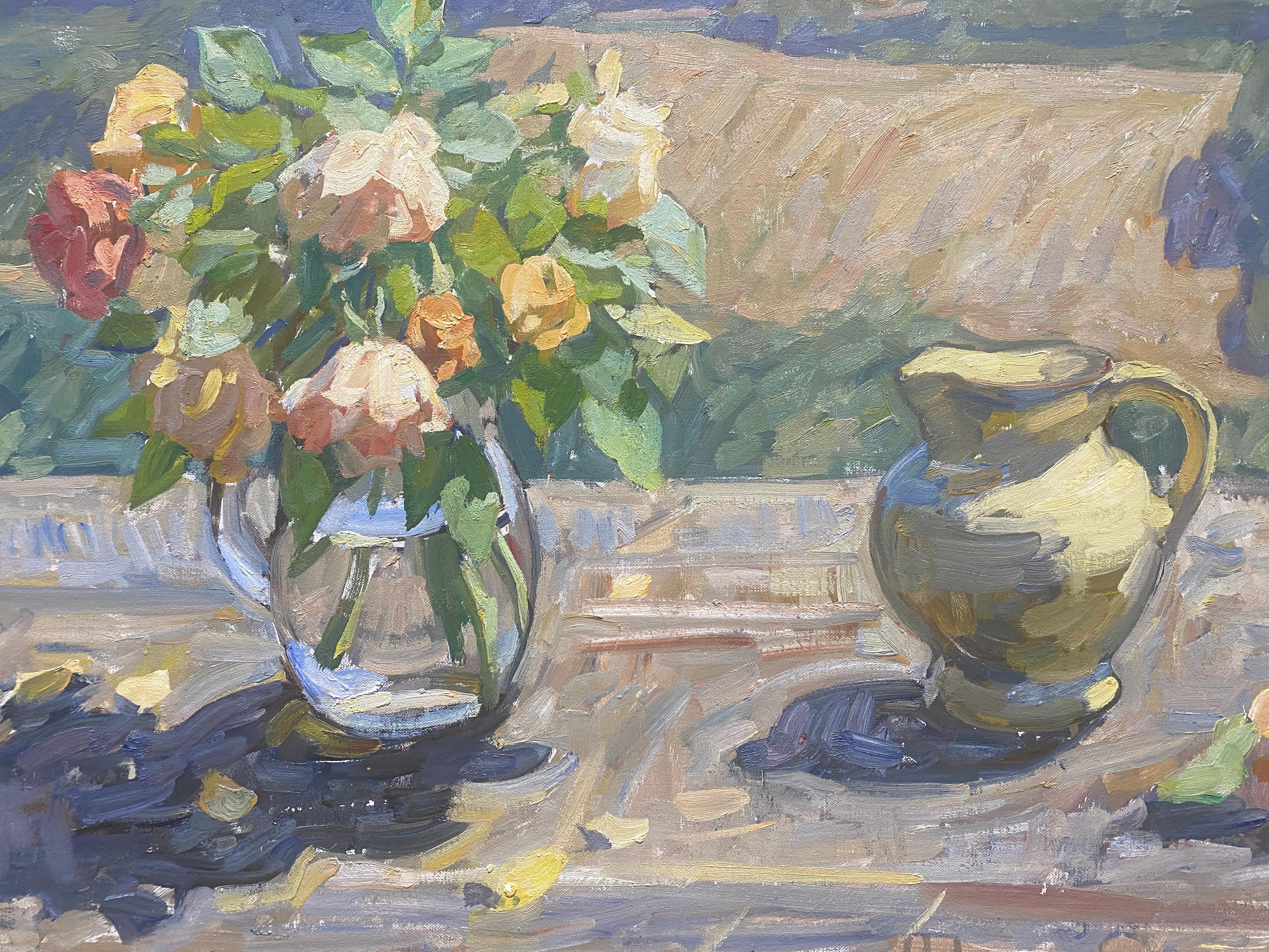 An oil painting that acts as both a still life, and a landscape. The still life consists of a yellow pitcher, a pair of orange roses resting beside it. A glass pitcher, holds a bouquet of orange roses, with leafy greens, and water reflecting and