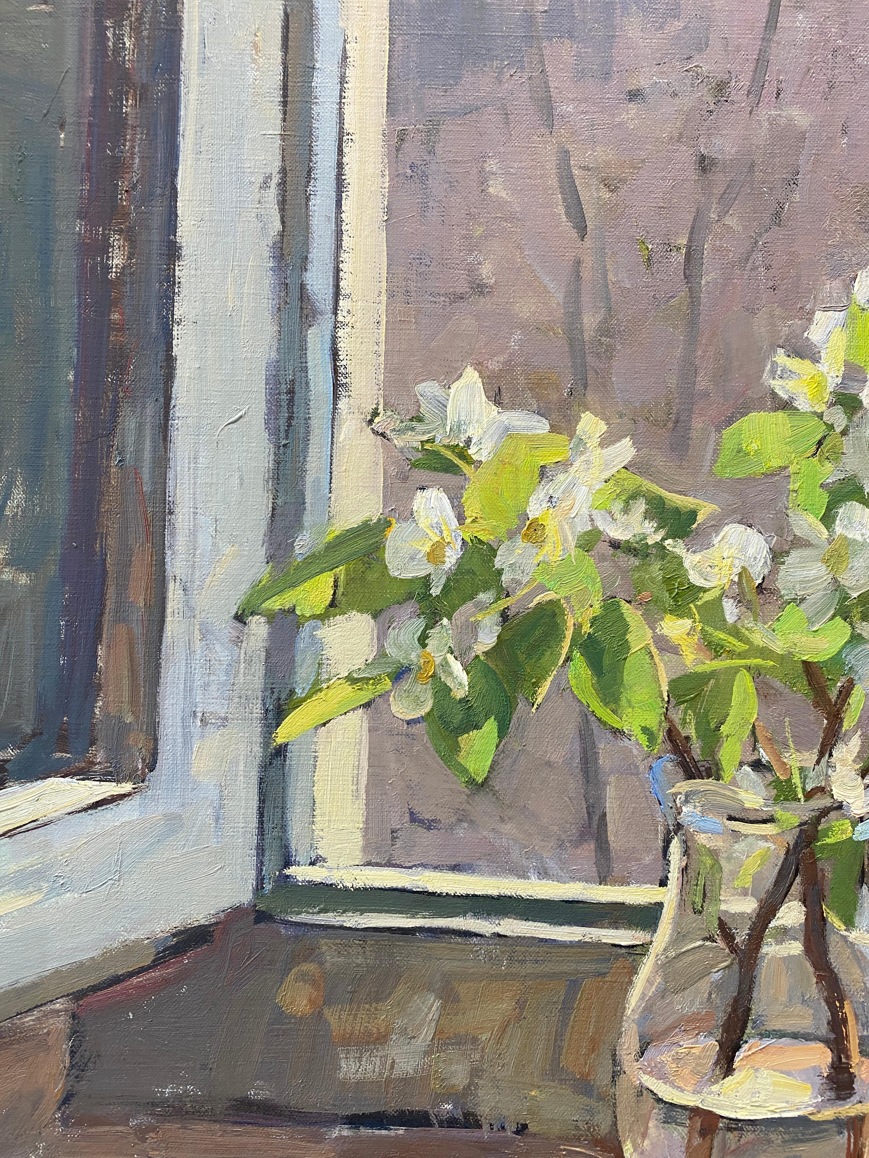 An oil painting that acts as both a still life, and an interior painting. A glass pitcher holds a pair of branches from a pear tree, flowering white pear blossoms reach upward amidst large green leaves. A glass paned window half open, gives fresh