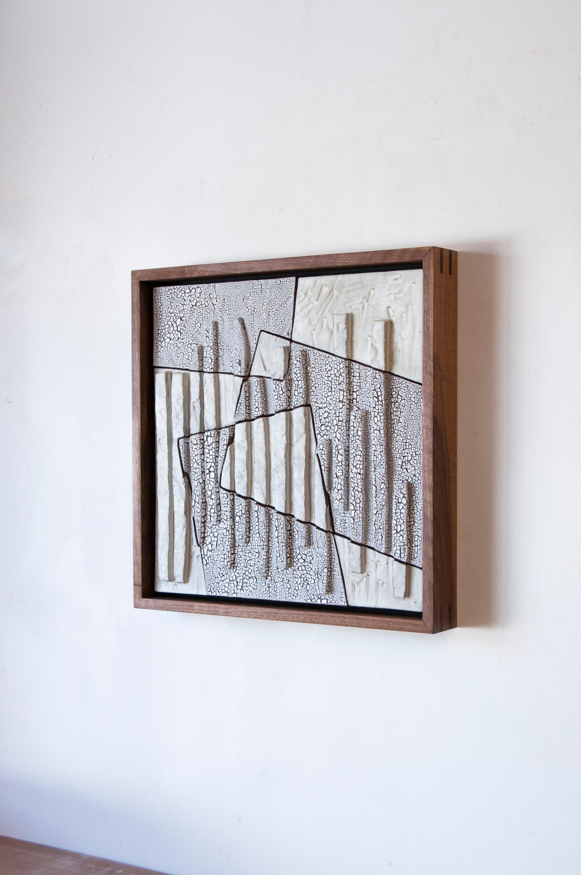 This minimalist ceramic wall sculpture is a beautiful handmade piece by American artist Ben Medansky, which includes a walnut wood frame. This wooden framed wall sculpture is made of neutral colored terracotta tiles covered in a textured glaze,