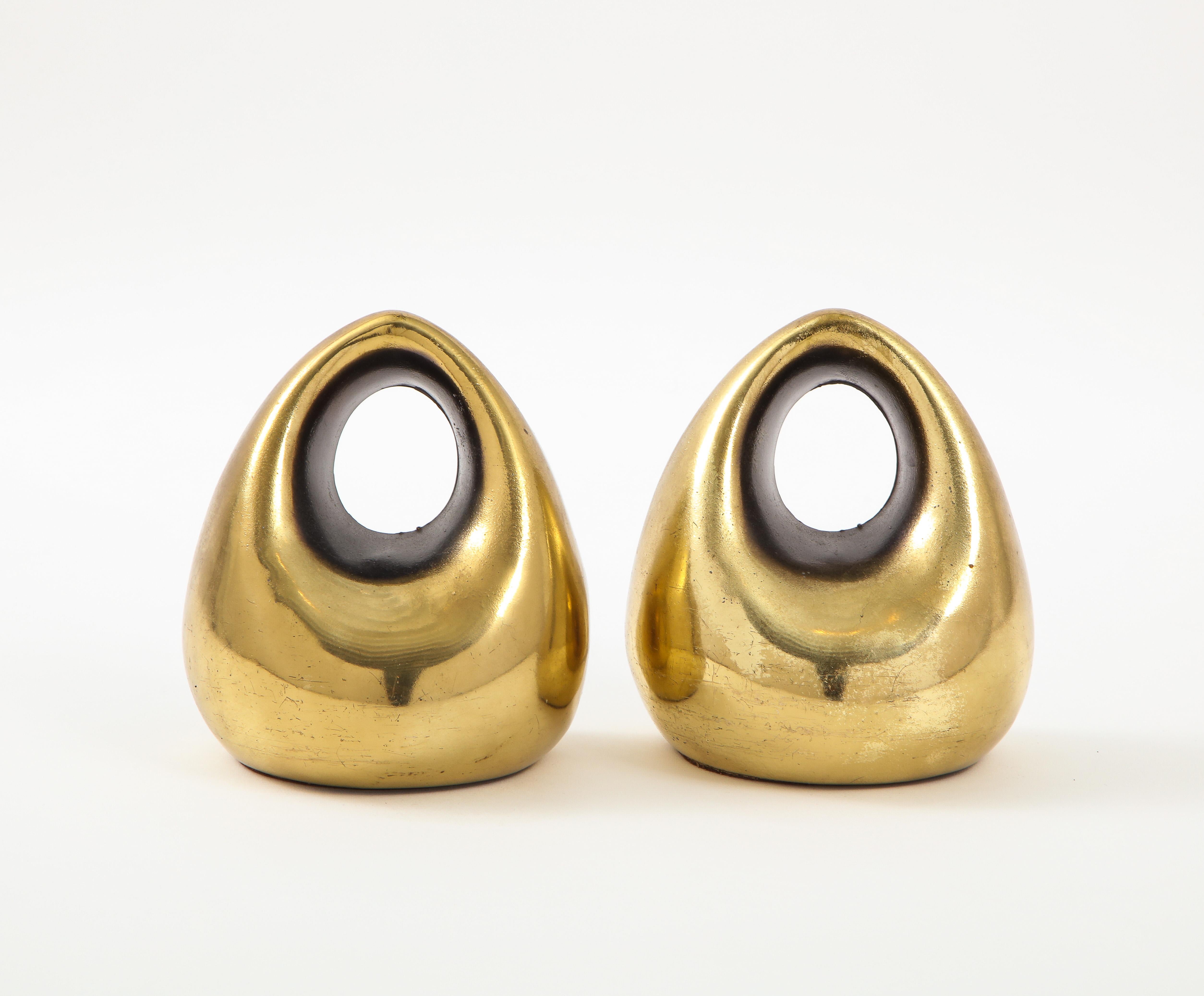 Ben Seibel bookends, brass orb. Rounded sculptural bookends with cutout. Original brass plated finish shows scratches, signs of wear, and crazing. 

Seibel, after studying painting, sculpture and architecture, set up his own studio in Post- War