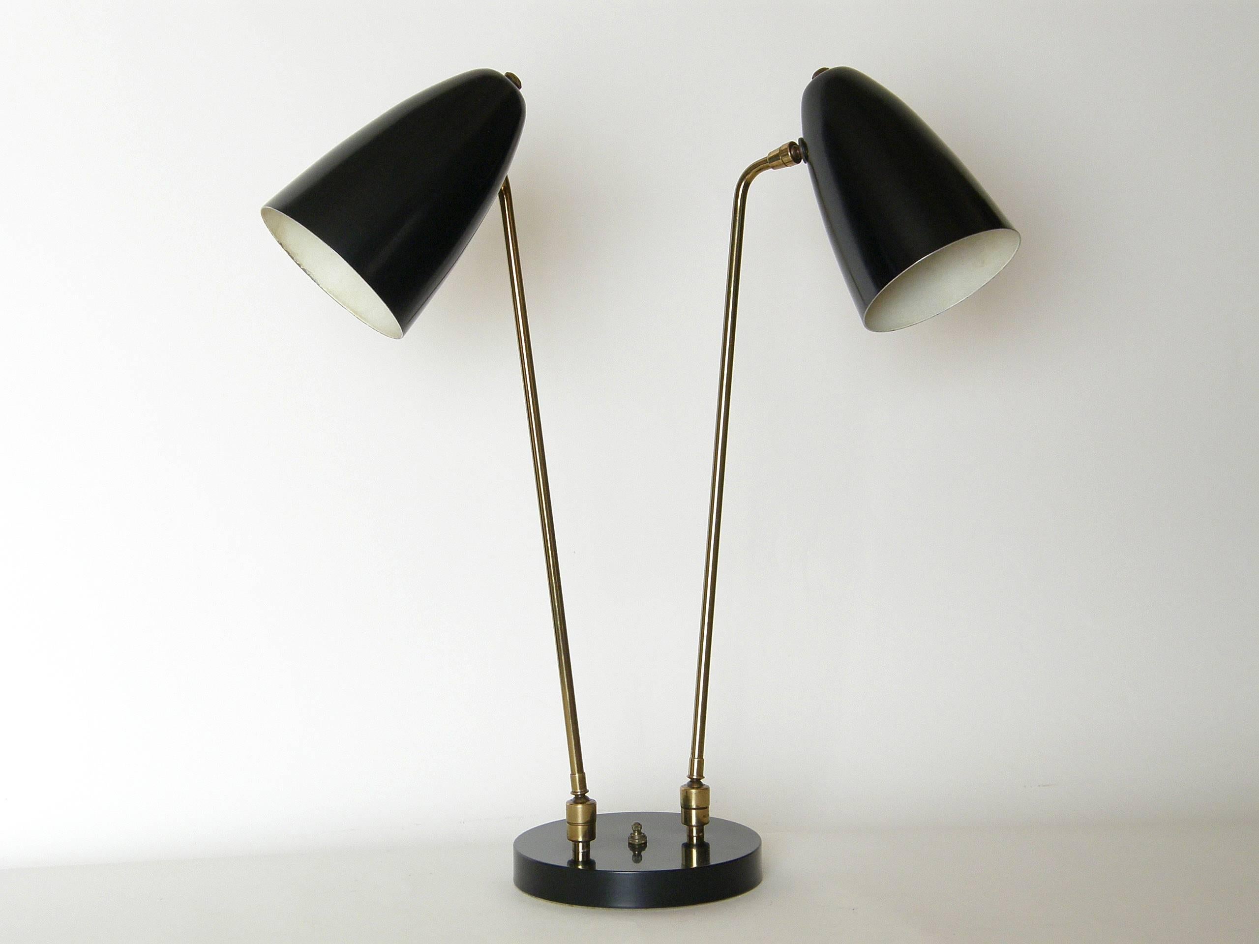 This versatile table lamp was designed by Ben Seibel, circa 1951, and sold through Raymor. The long arms have pivoting ball and socket joints at both the base ends and the points of attachment to the cone shaped shades. This gives the lamp a wide