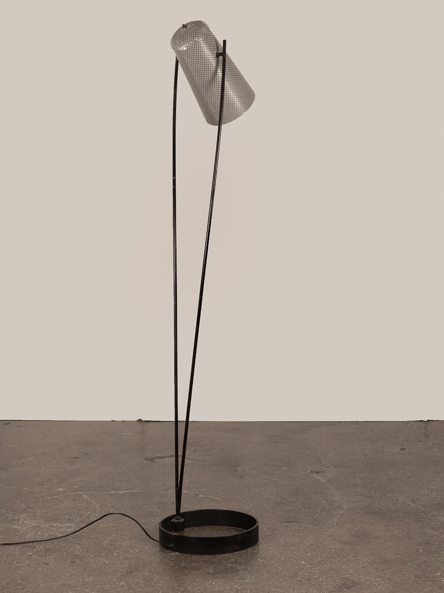 Minimalist 5000-series floor lamp by Ben Seibel, designed as part of a “distinctive group of flexible lighting units” for the design importer Raymor. Adjustable perforated-aluminum shade in original grey finish with some paint loss, lined with paper