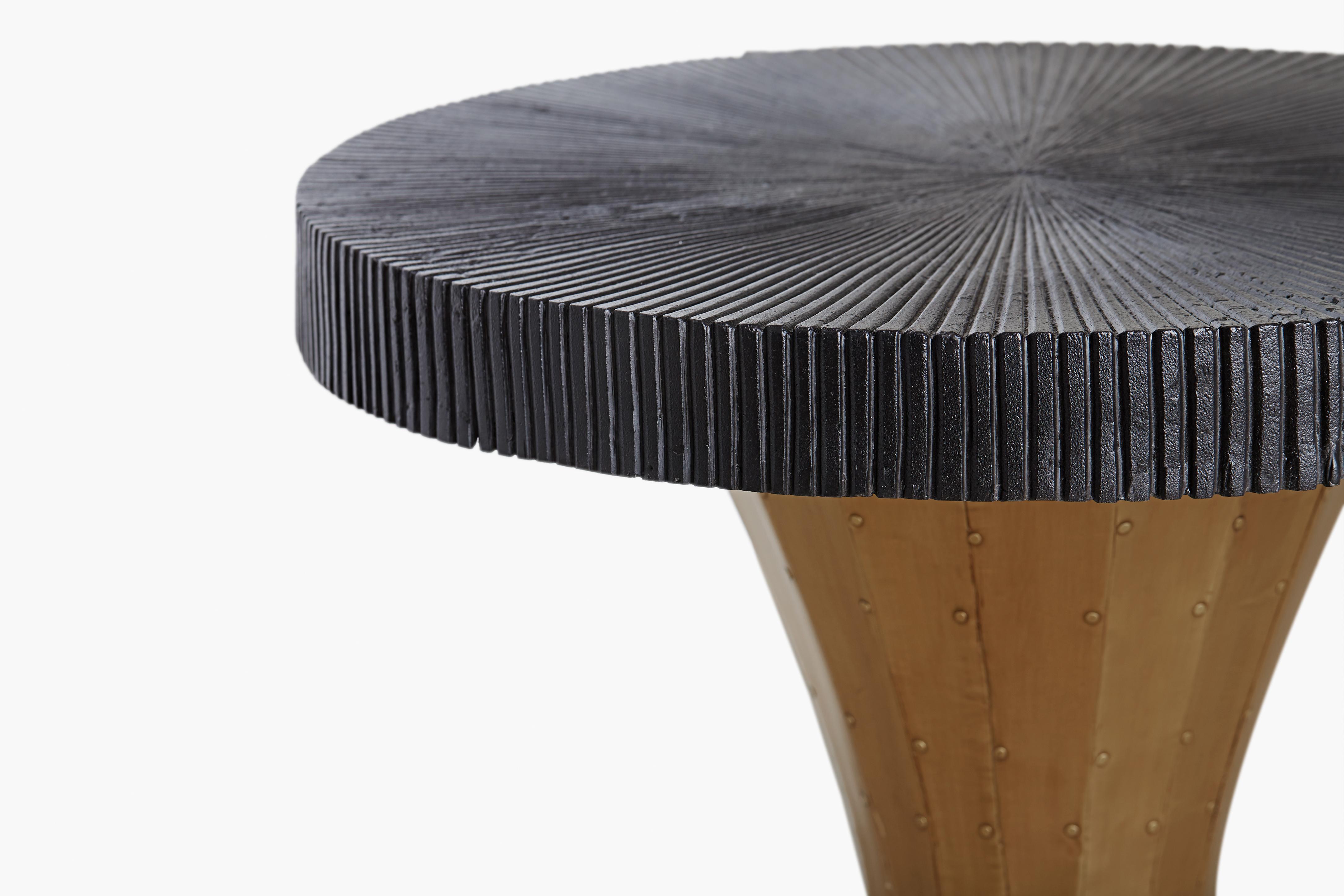 The gleaming curved brass paneled pedestal of the Raine side table is elegantly contrasted with a generous round blackened table top with a subtle sunburst pattern.
 