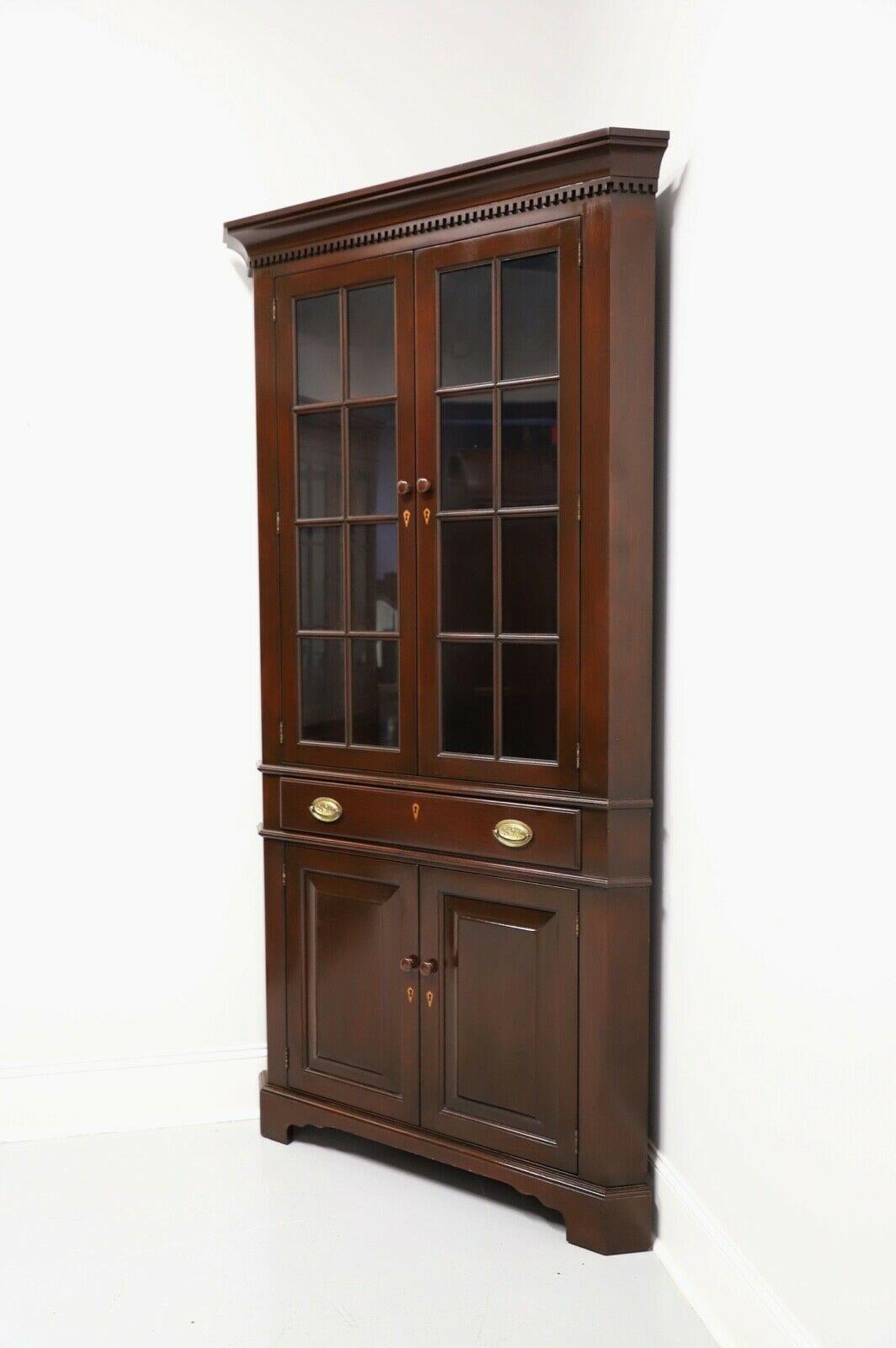 An extra tall Chippendale style corner cabinet by Benbow's of Greensboro, North Carolina, USA. Solid mahogany with wood knobs to doors, brass drawer & hinge hardware, crown & dentil molding and bracket feet. Upper cabinet features three fixed plate
