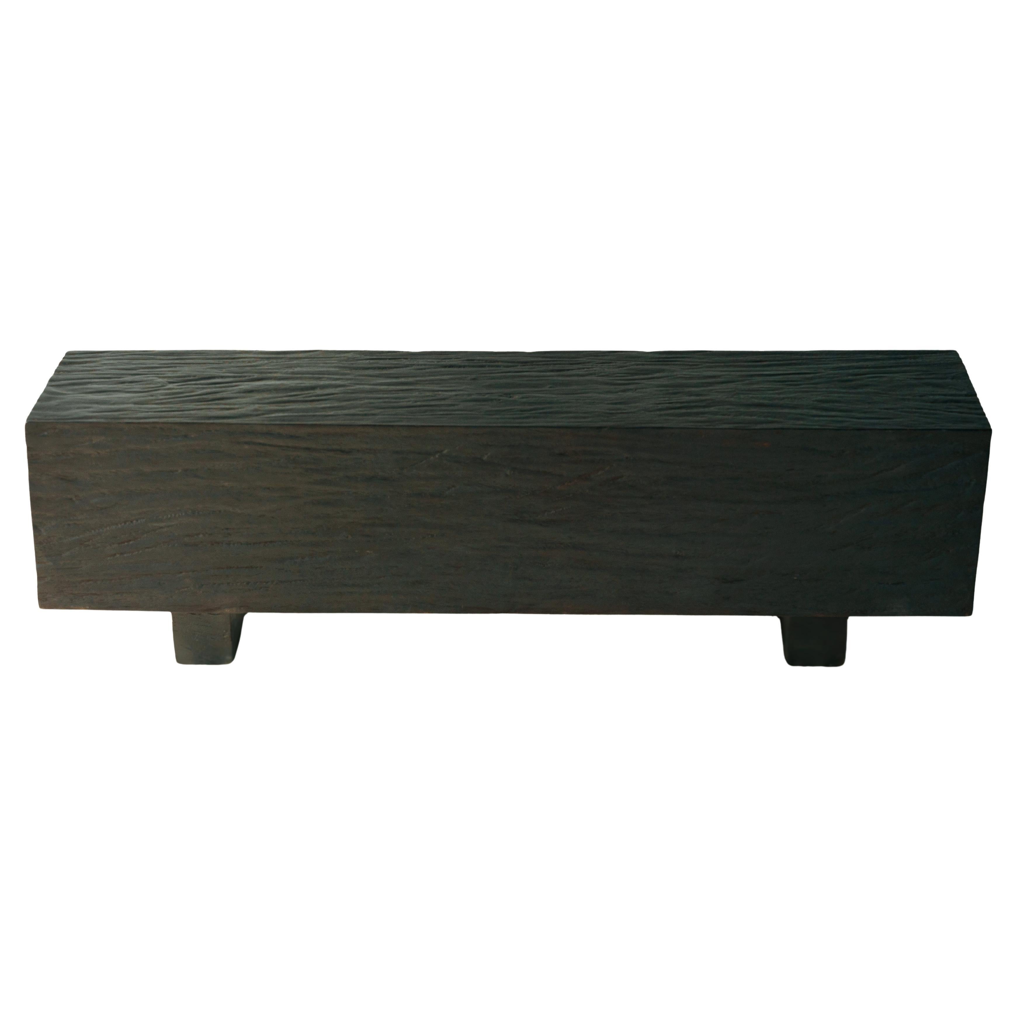 Le banc 01 est une pièce audacieuse et fondée, fabriquée en bois massif avec un accent sur la texture et la forme. Le design monolithique met en valeur le grain naturel du bois, avec une surface sculptée à la main qui introduit de la profondeur et
