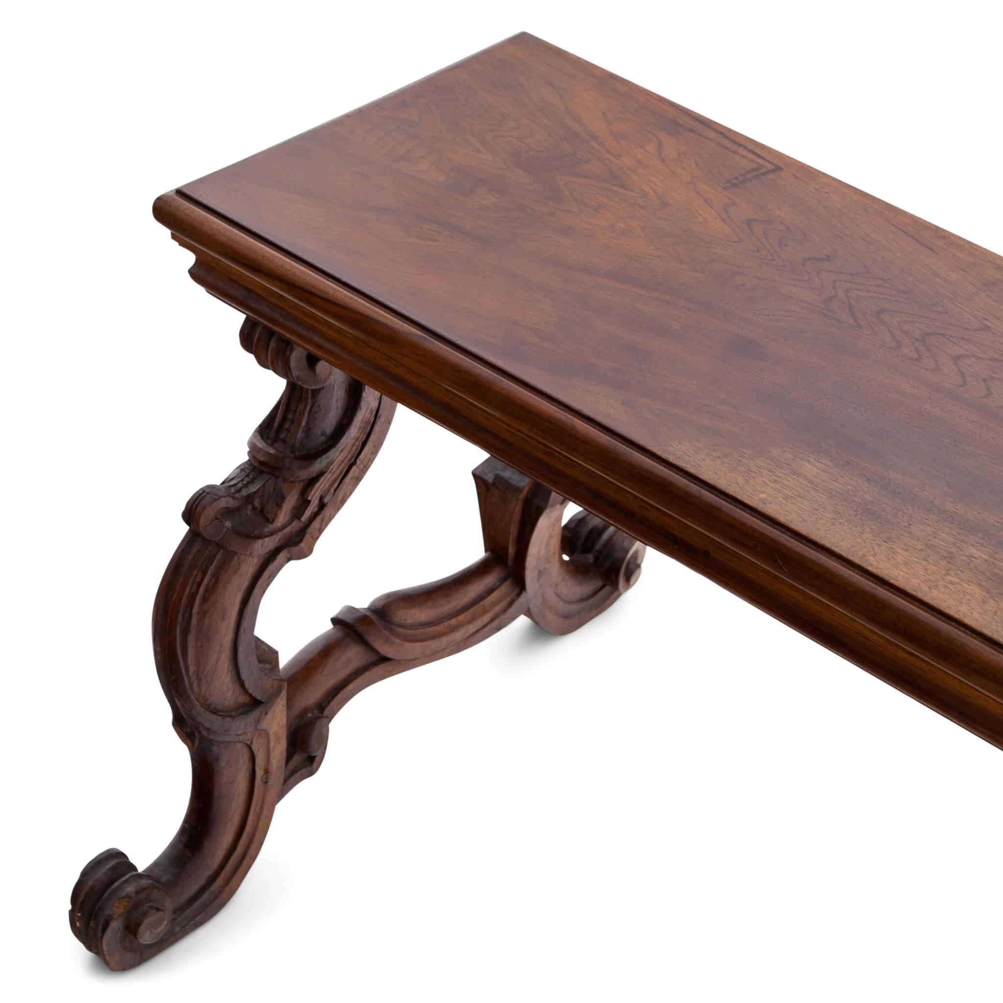 Baroque walnut bench with a rectangular seat and protruding volute legs.